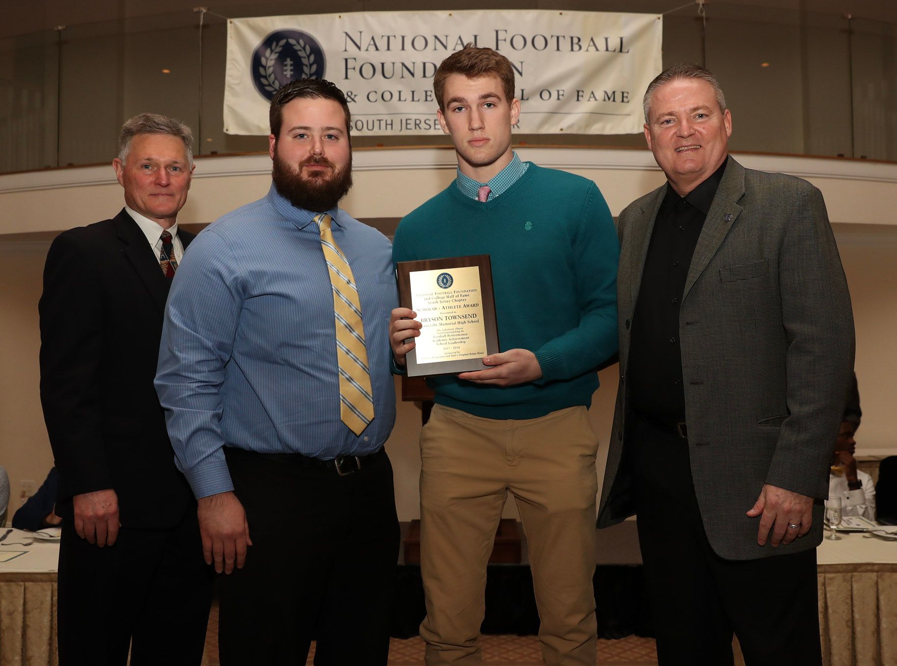 a group of men are posing for a picture in front of a national football foundation banner