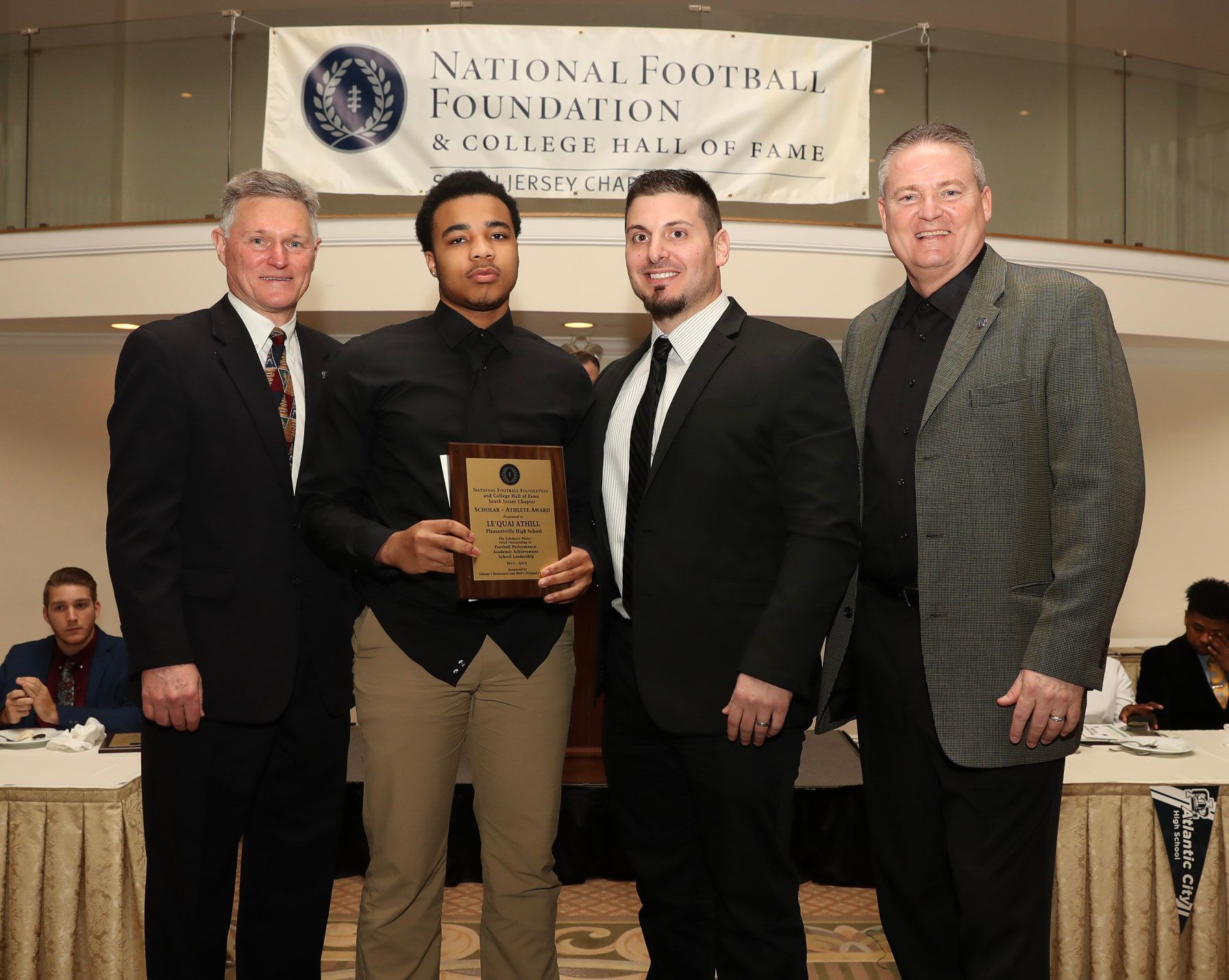 a group of men standing in front of a national football foundation banner