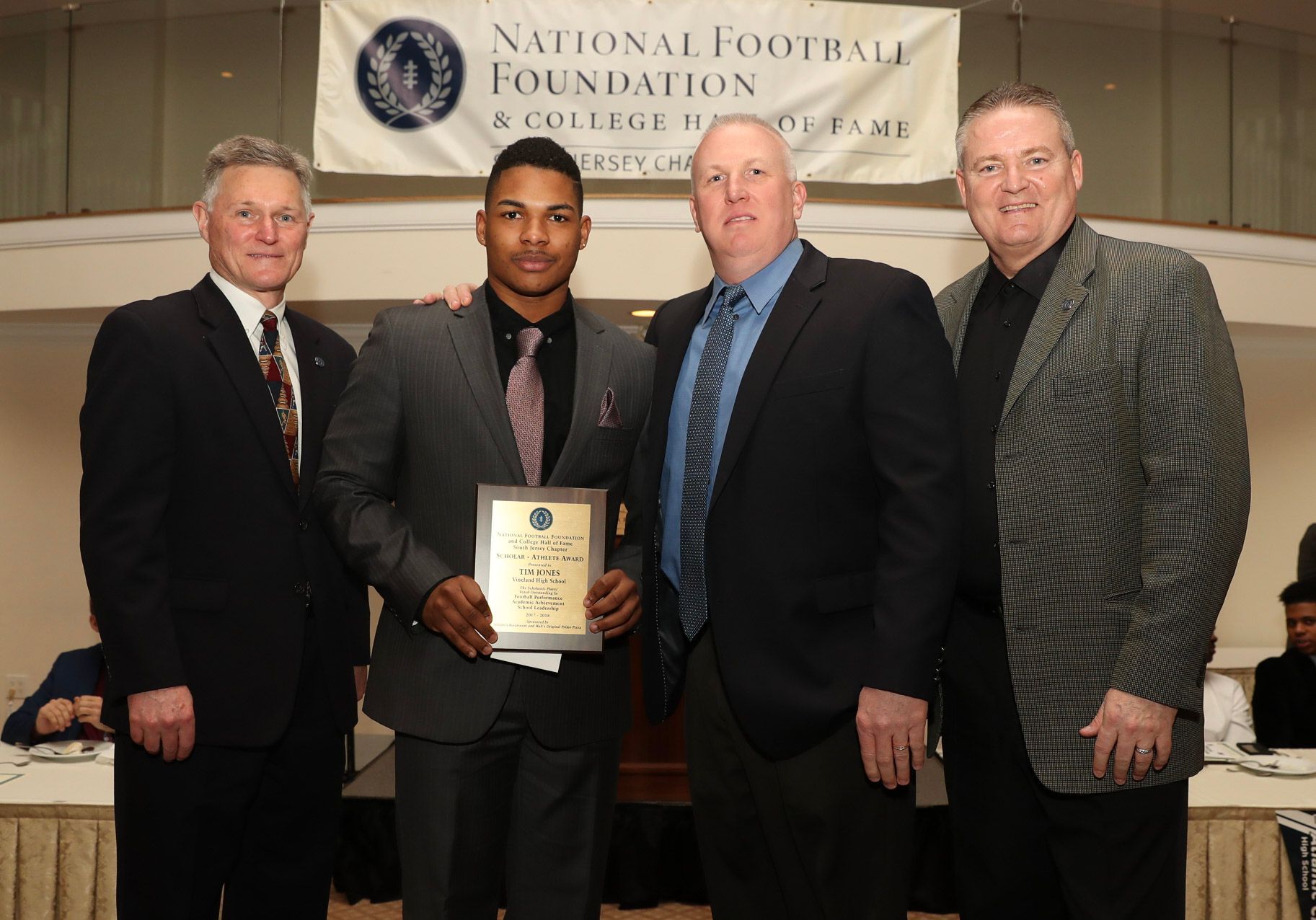 a man is holding a plaque in front of a national football foundation banner