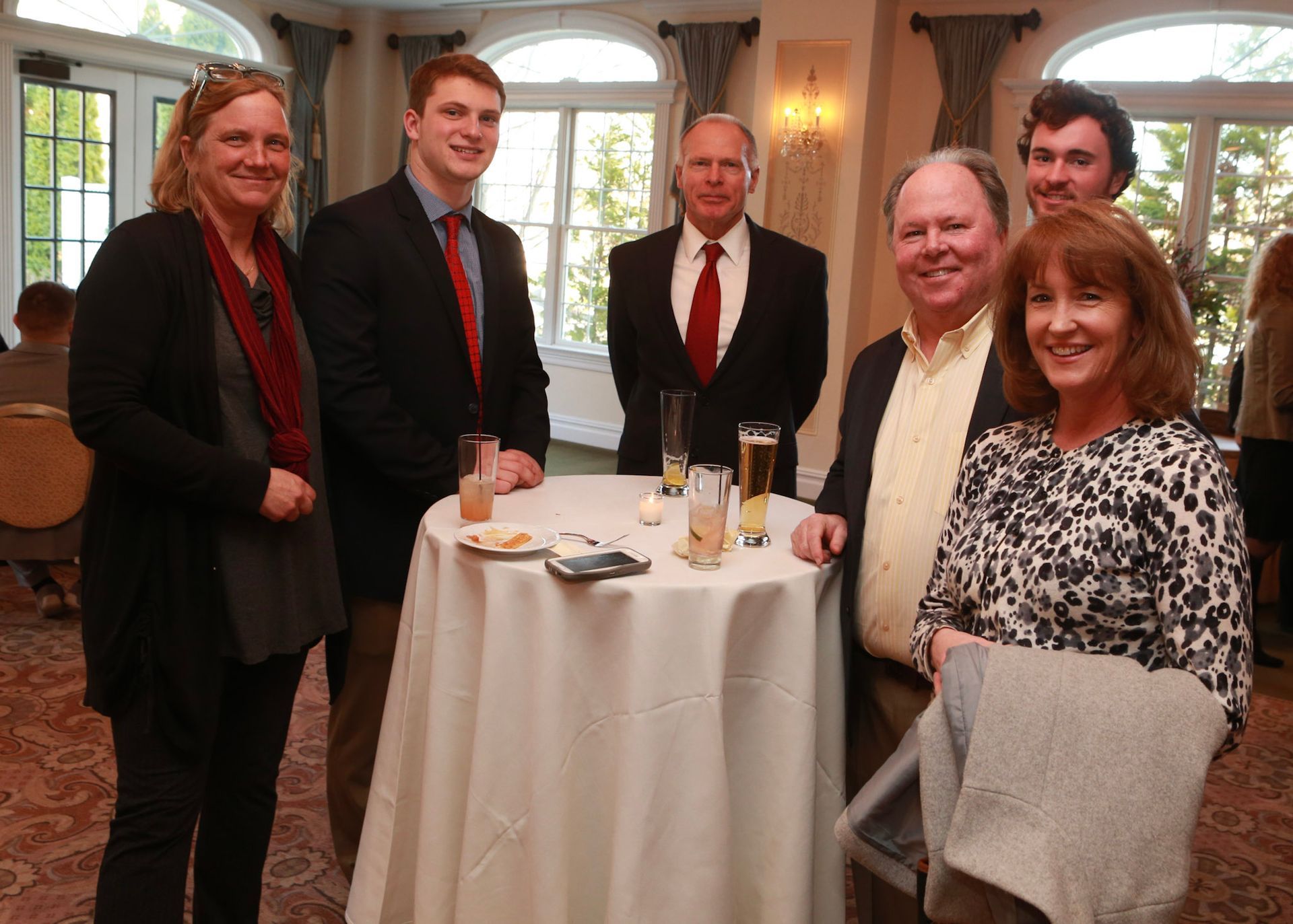a group of people standing around a table with drinks on it