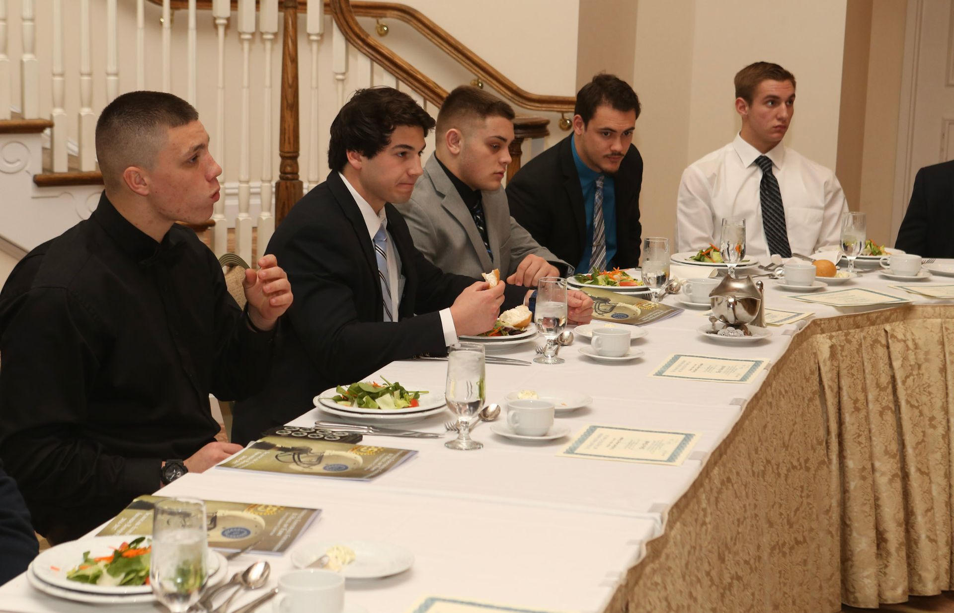 a group of men sit at a long table eating food
