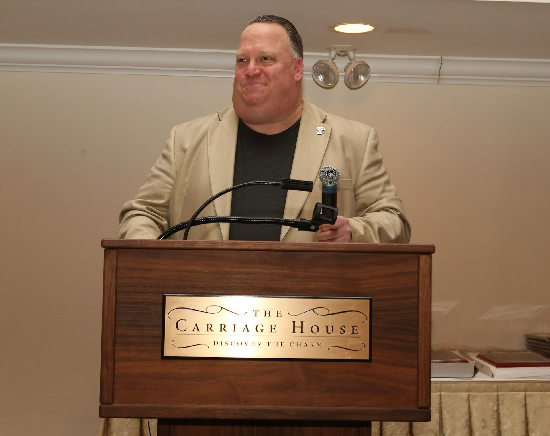 a man stands at a podium that says heritage house