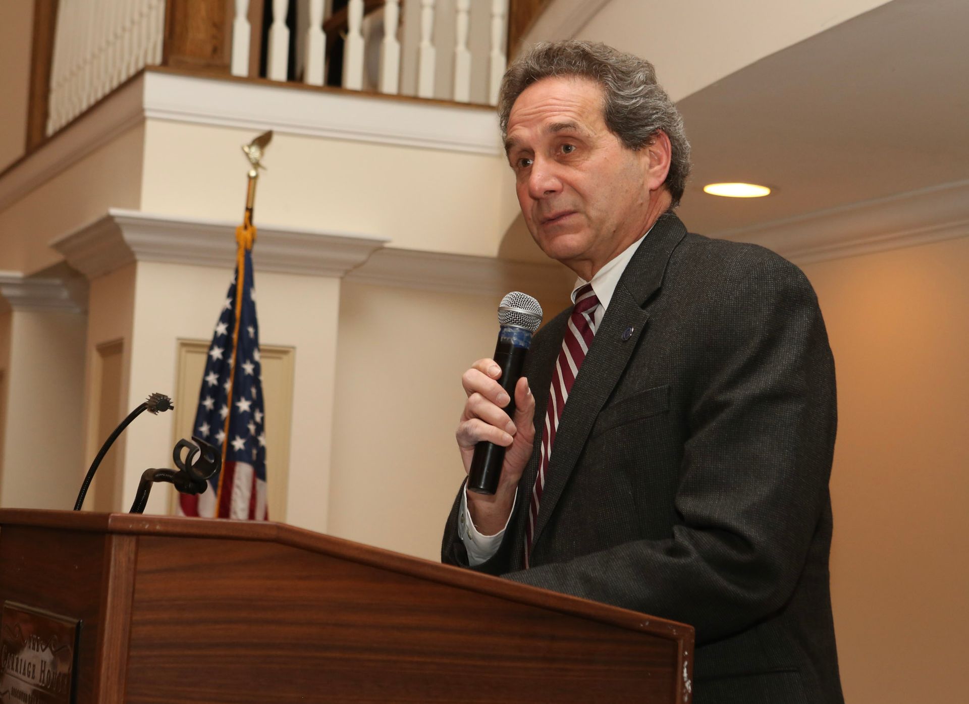 a man in a suit and tie stands at a podium holding a microphone