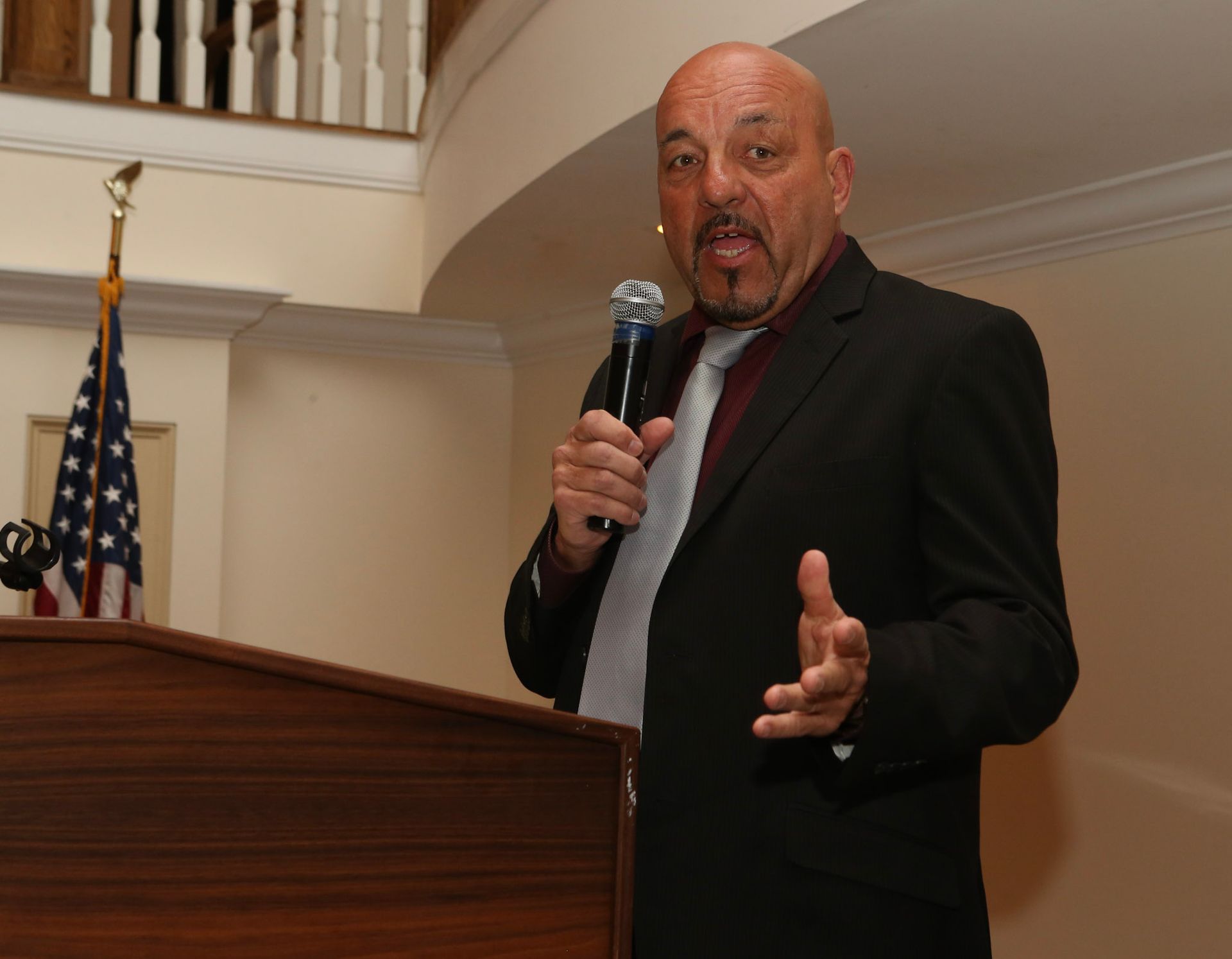 a man in a suit and tie is speaking into a microphone