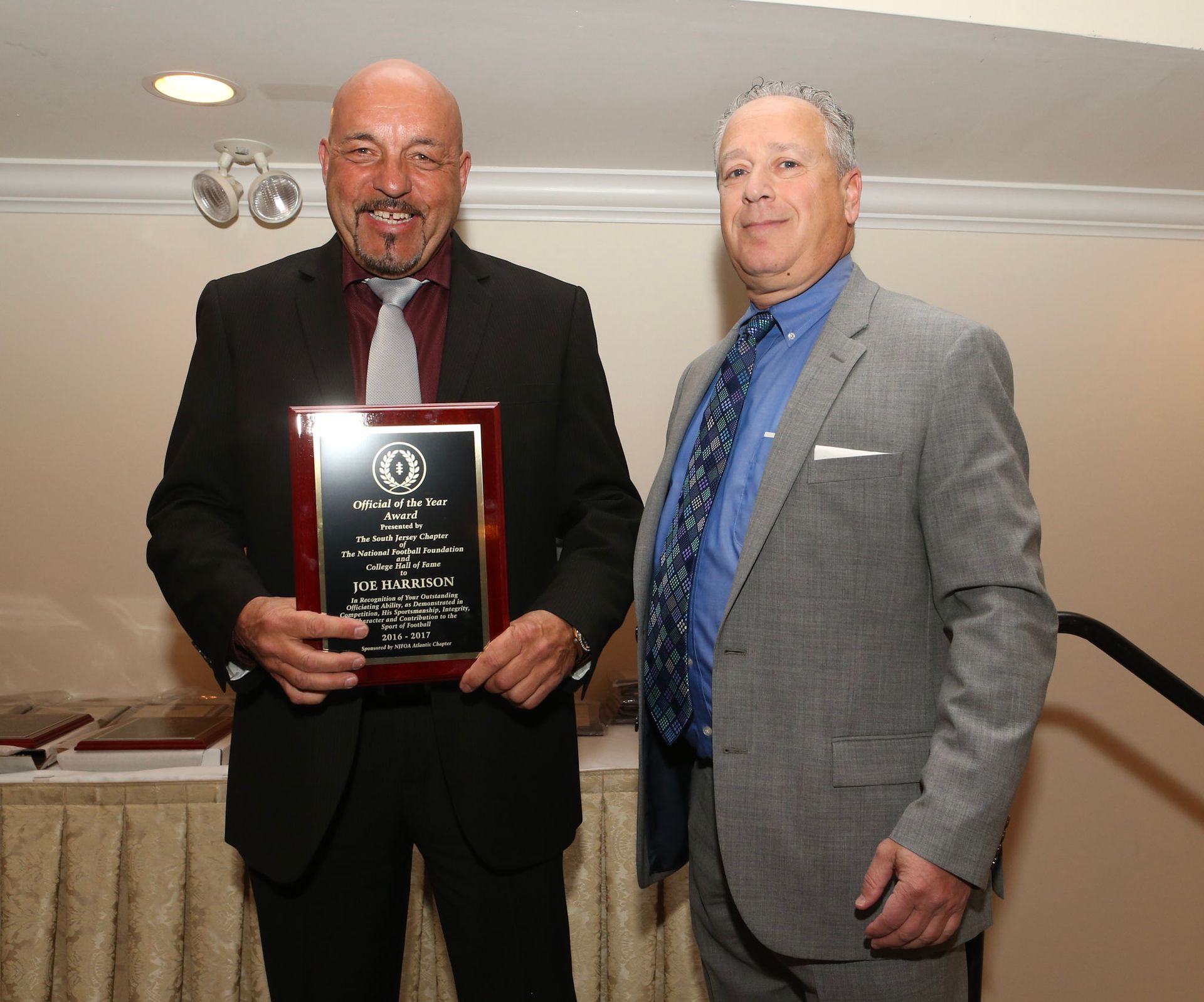 a man in a suit is holding a plaque that says ' a ' on it
