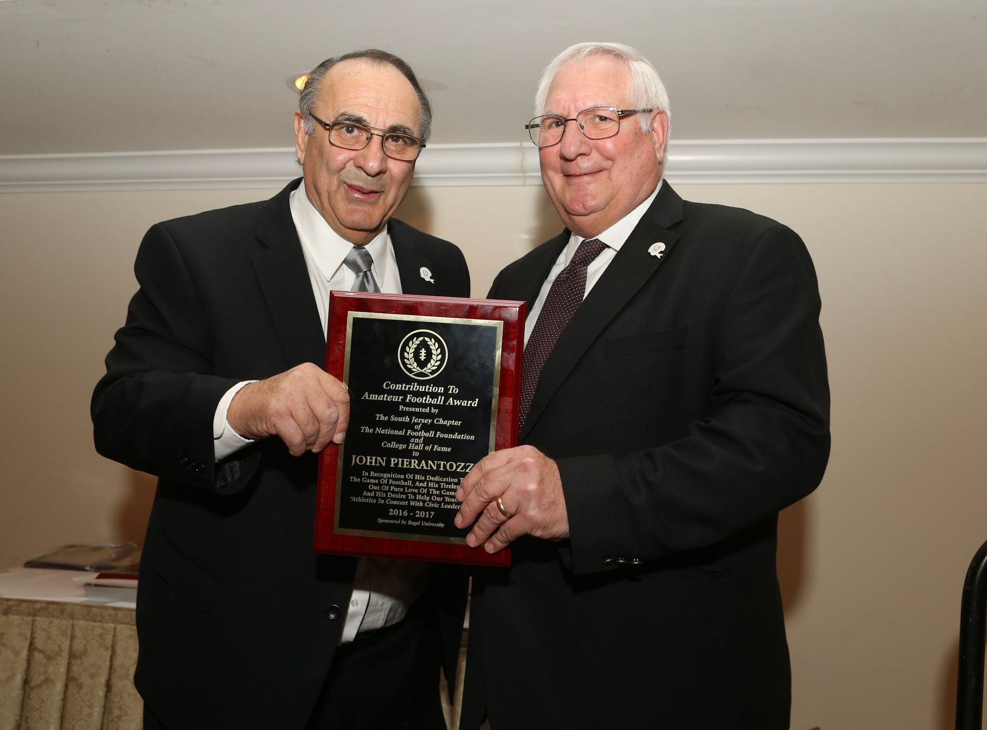 two men in suits and ties are holding a plaque