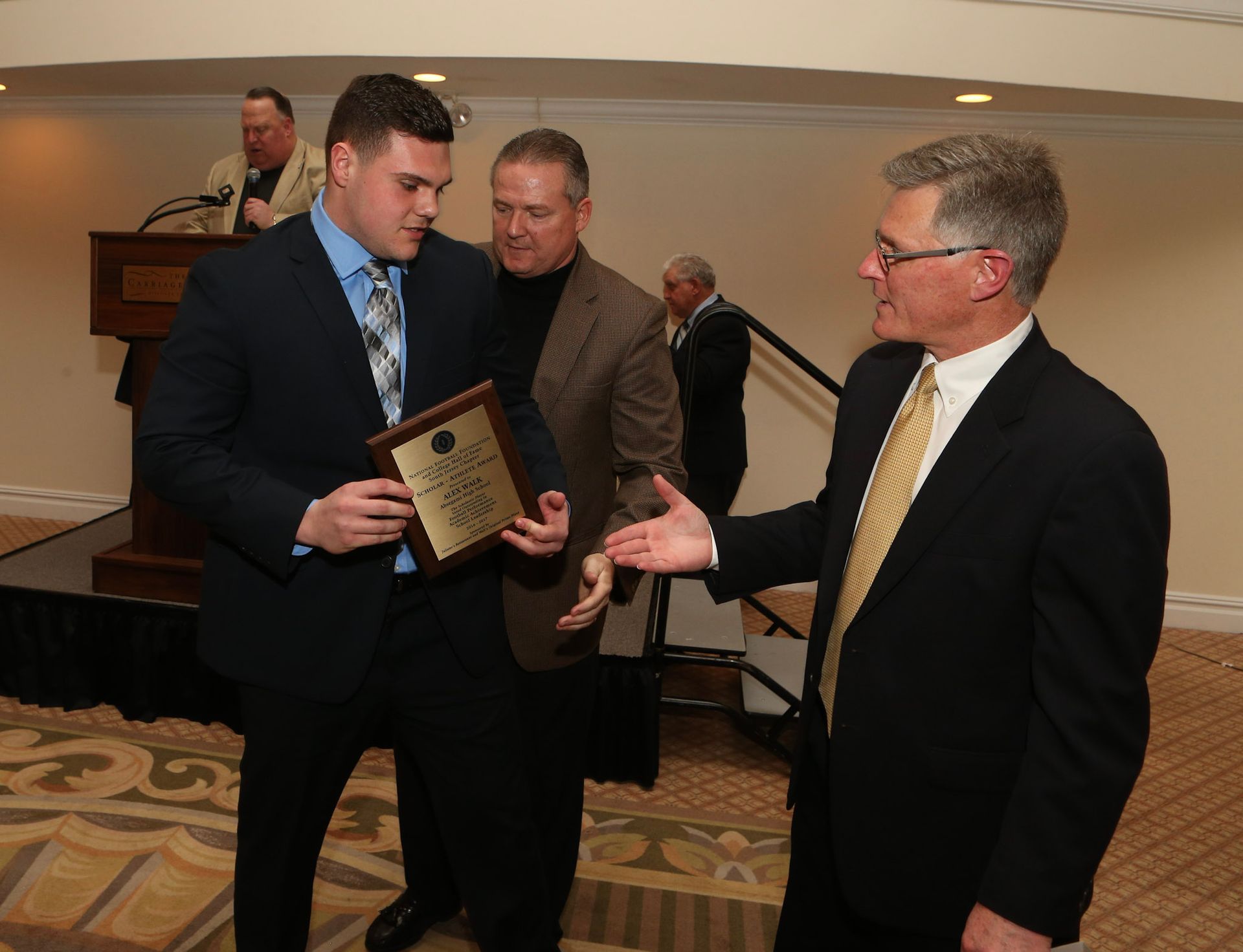 a man in a suit is holding a plaque that says ' winner ' on it