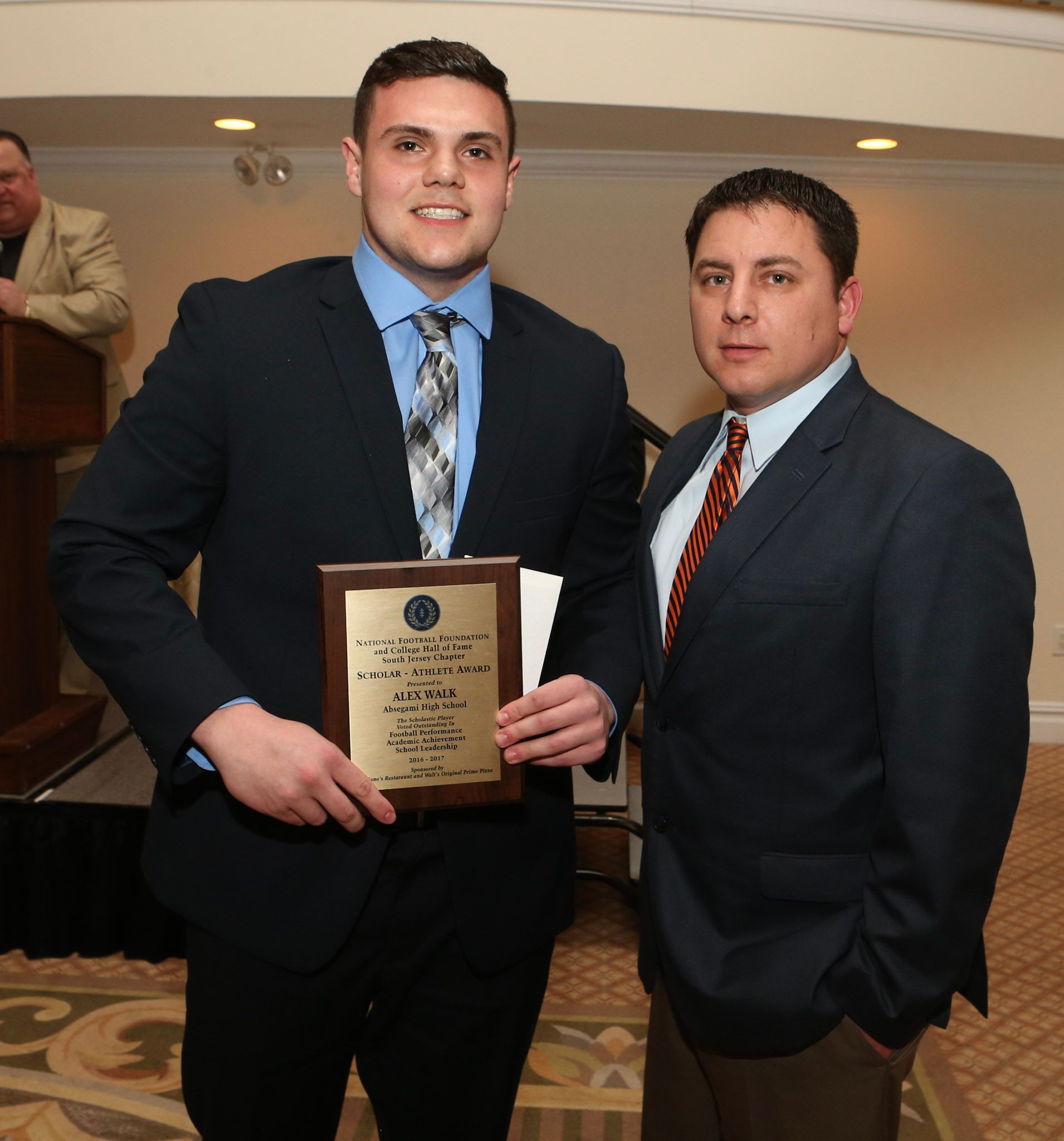 a man in a suit and tie is holding a plaque that says ' a ' on it