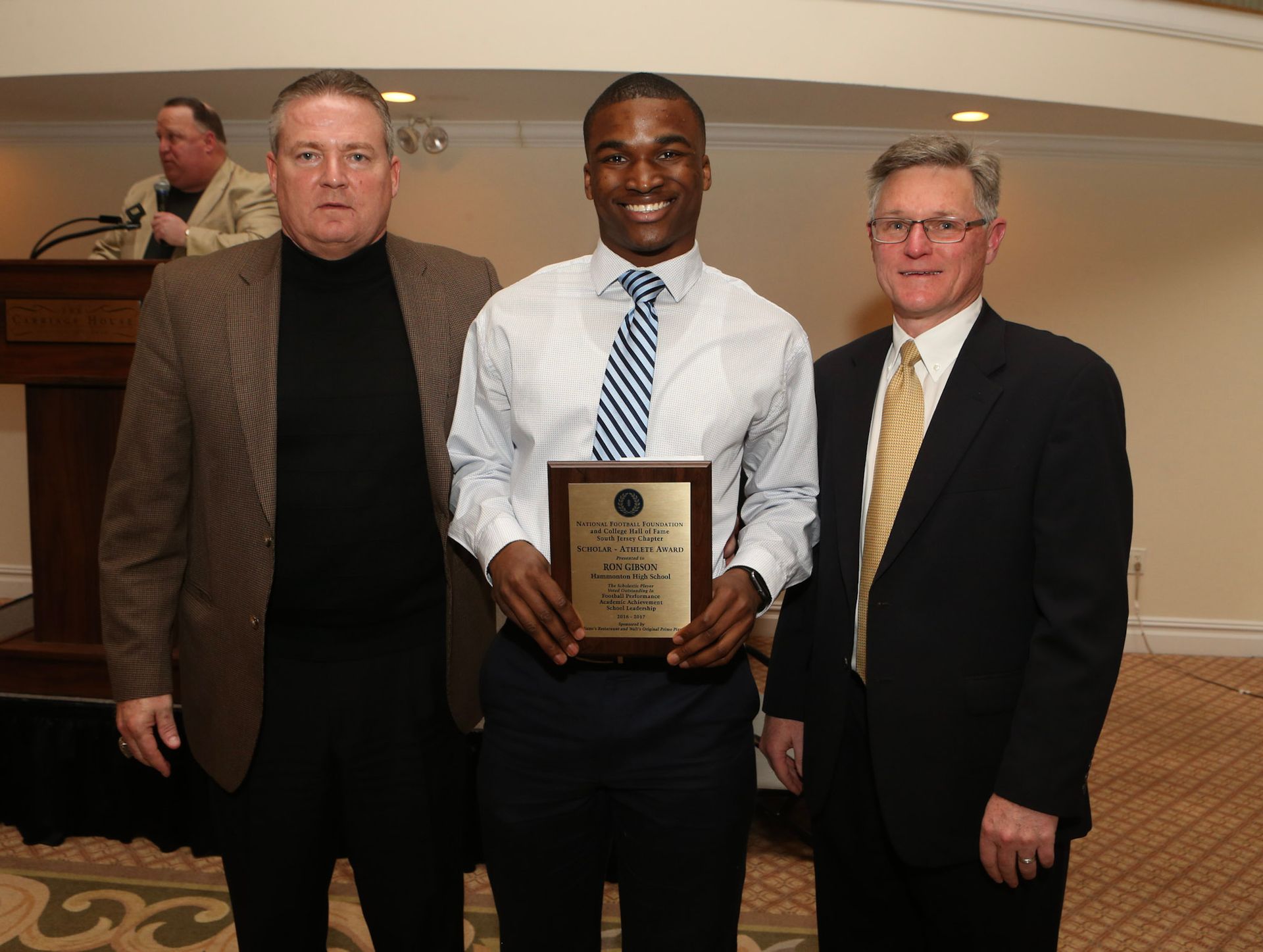a man in a white shirt and tie holds a plaque that says ' award ' on it