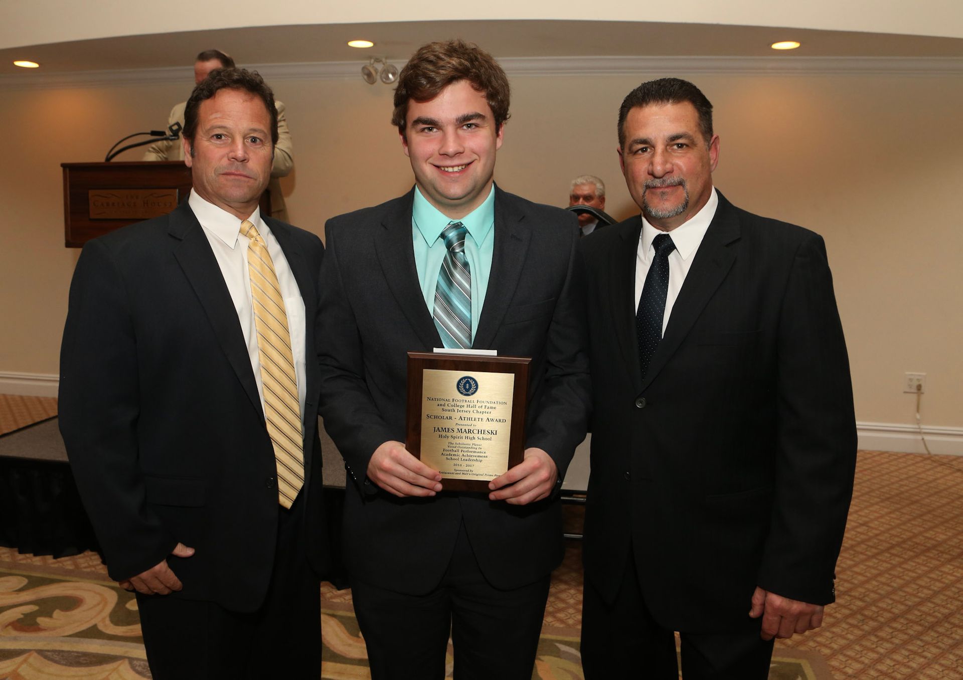 a man in a suit and tie is holding a plaque