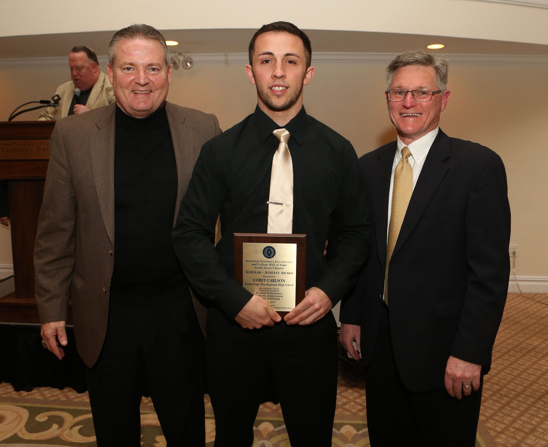 a man in a black shirt and tie is holding a plaque