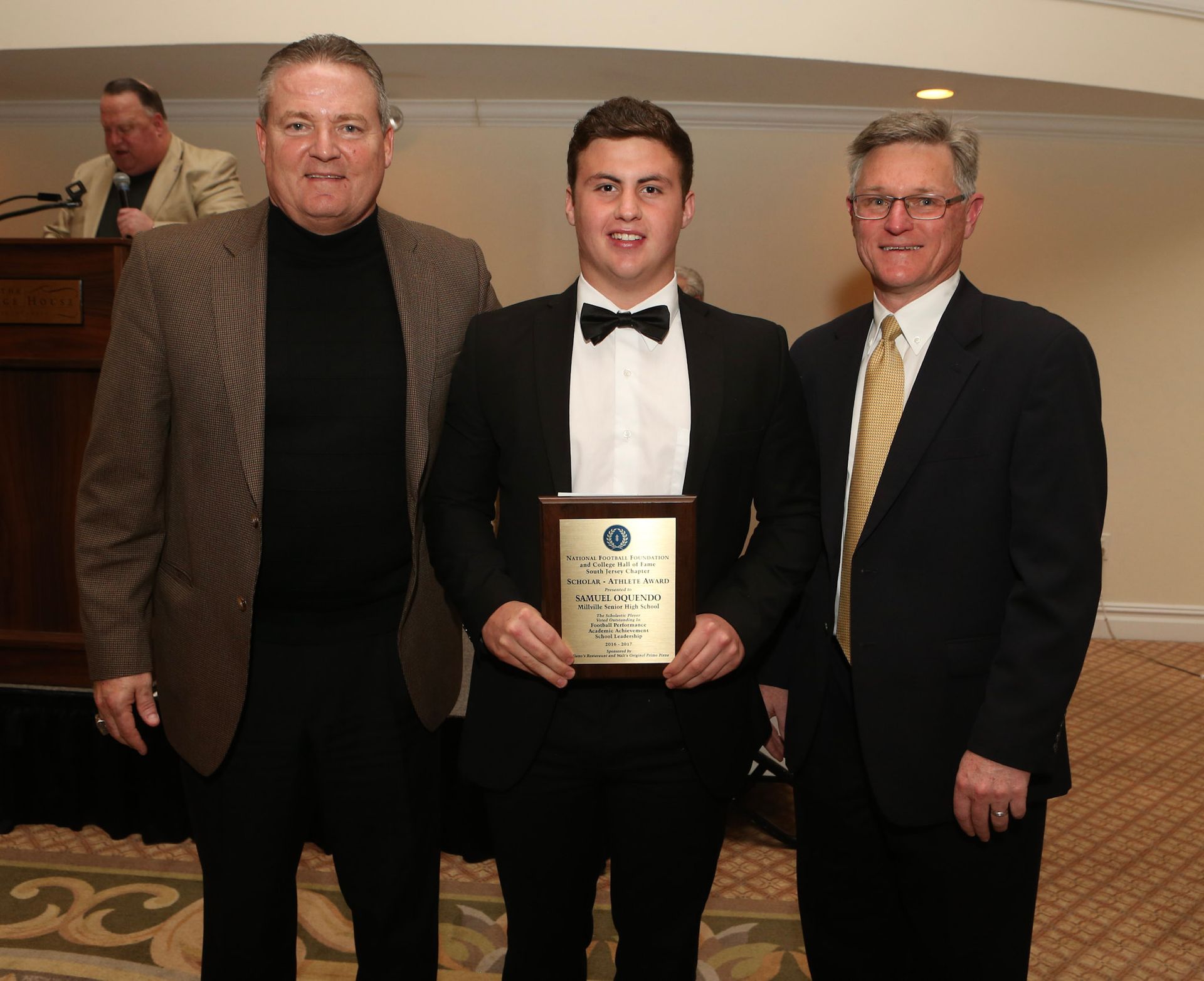 a man in a tuxedo is holding a framed certificate