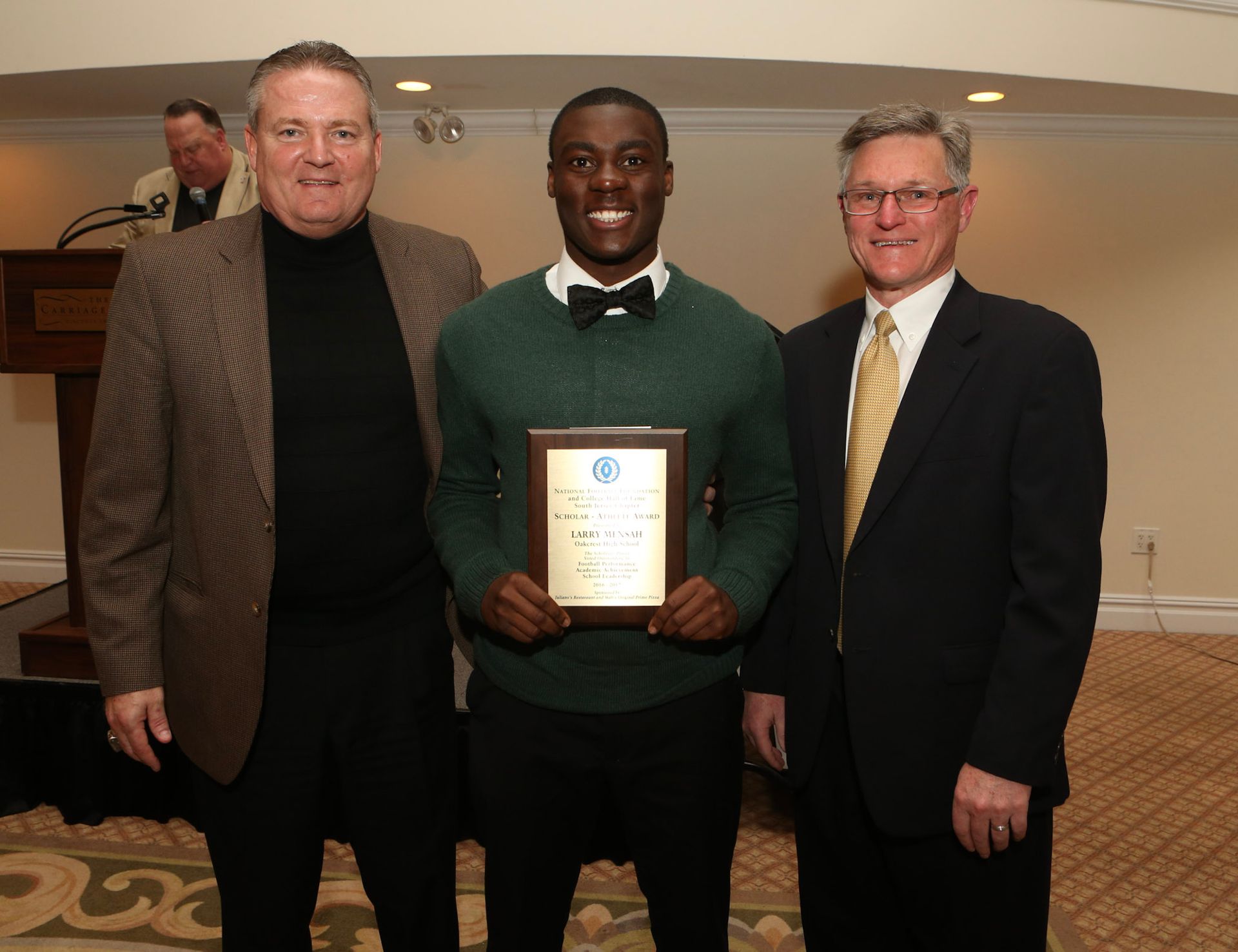 a man in a green sweater is holding a framed certificate