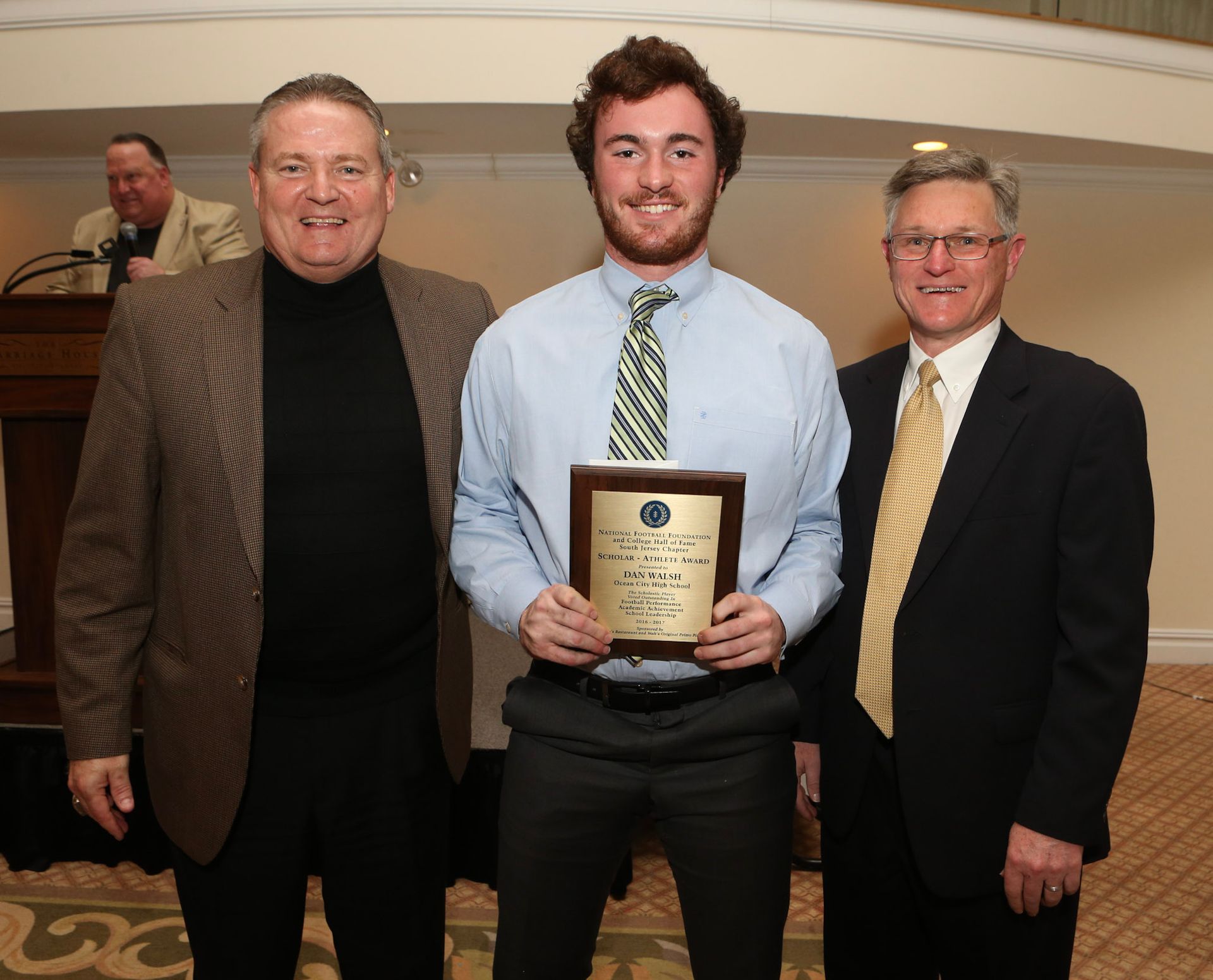 a man in a blue shirt and tie is holding a plaque