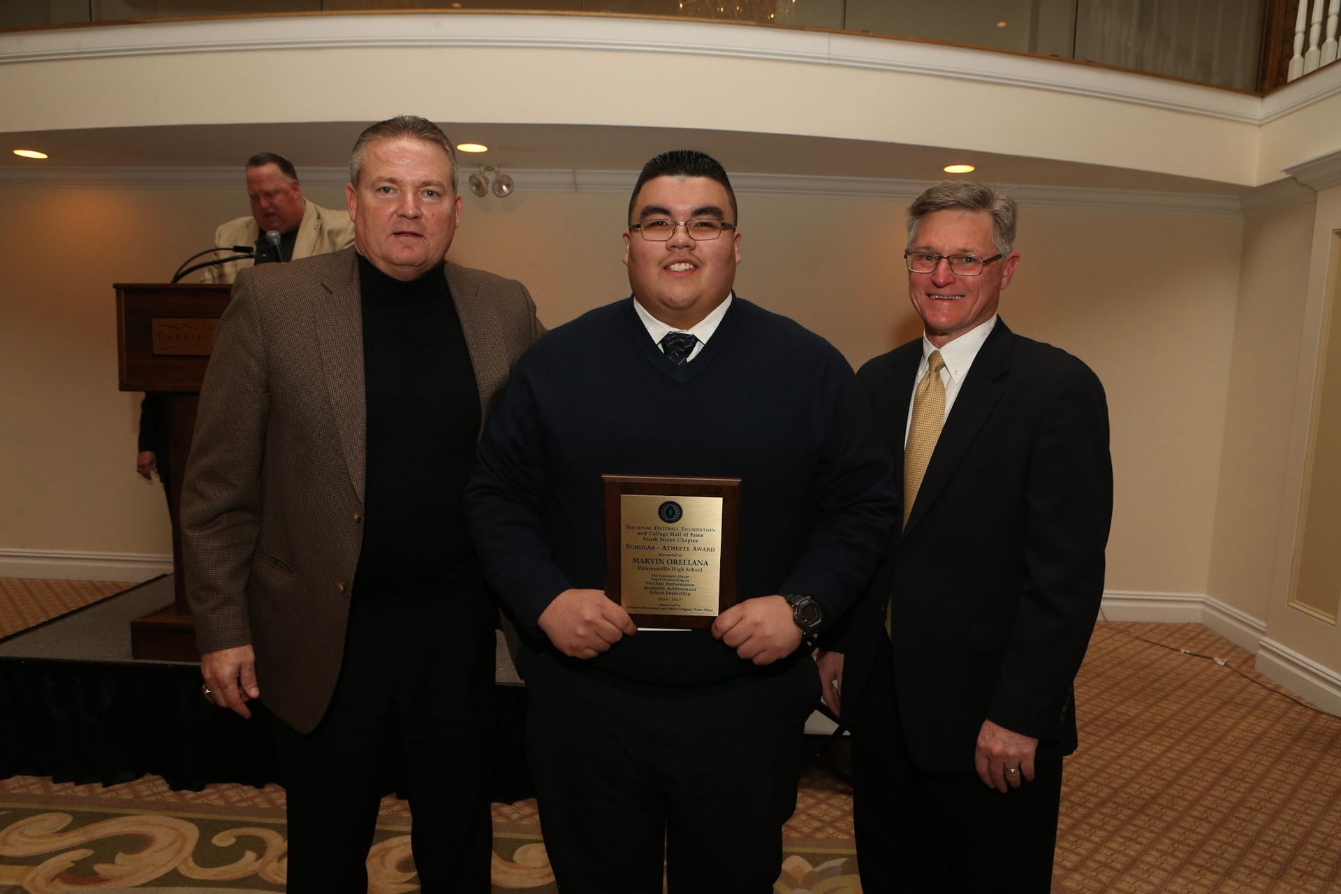 three men standing next to each other with one holding a plaque