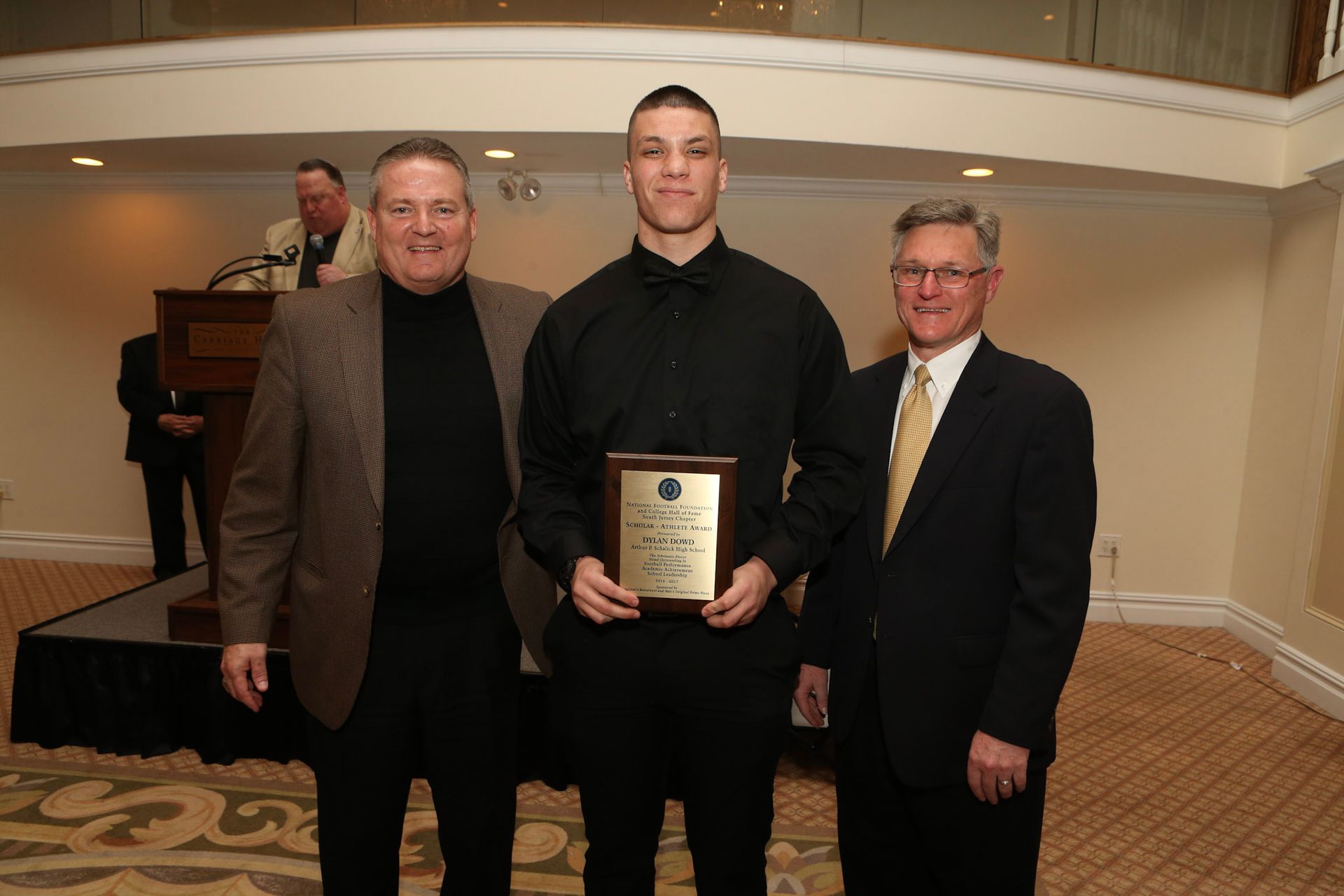 a man in a black shirt is holding a plaque that says ' a ' on it