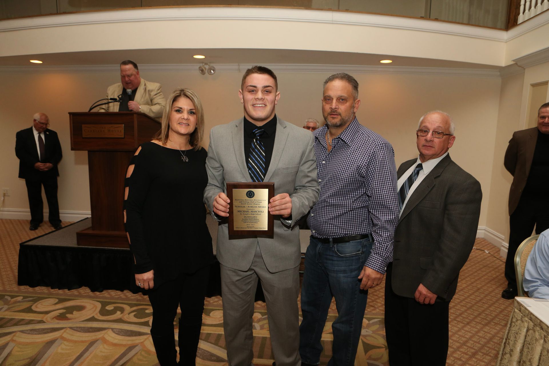 a man in a suit is holding a plaque that says ' a ' on it
