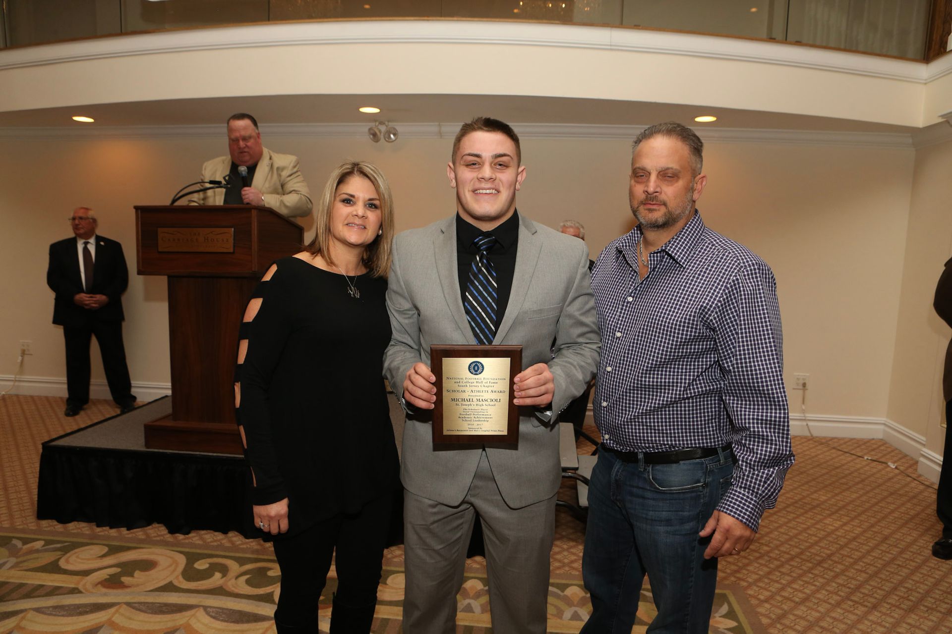 a man in a suit is holding a plaque that says ' excellence ' on it