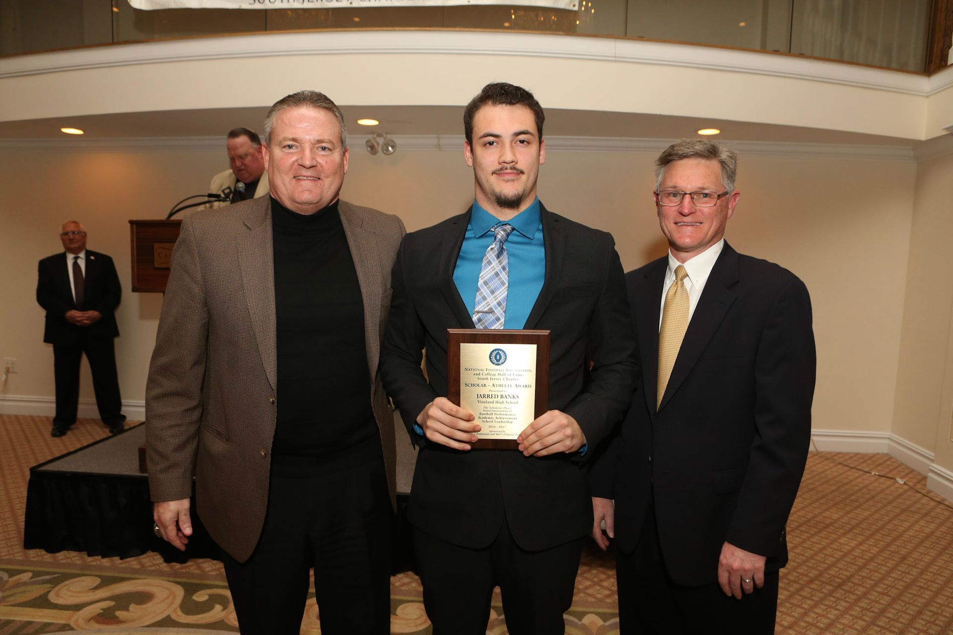 a man in a suit is holding a plaque with a cross on it