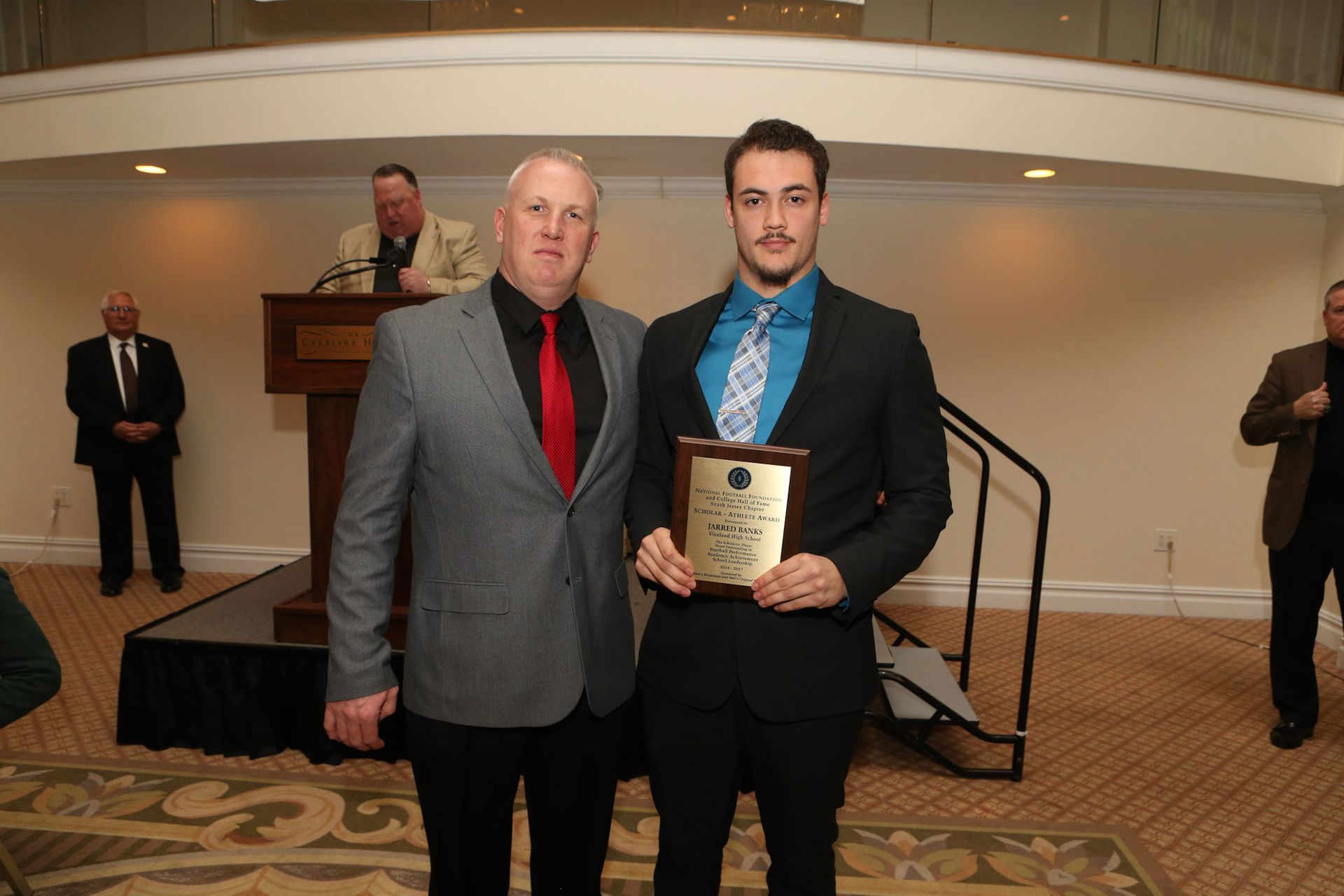 two men standing next to each other holding a plaque