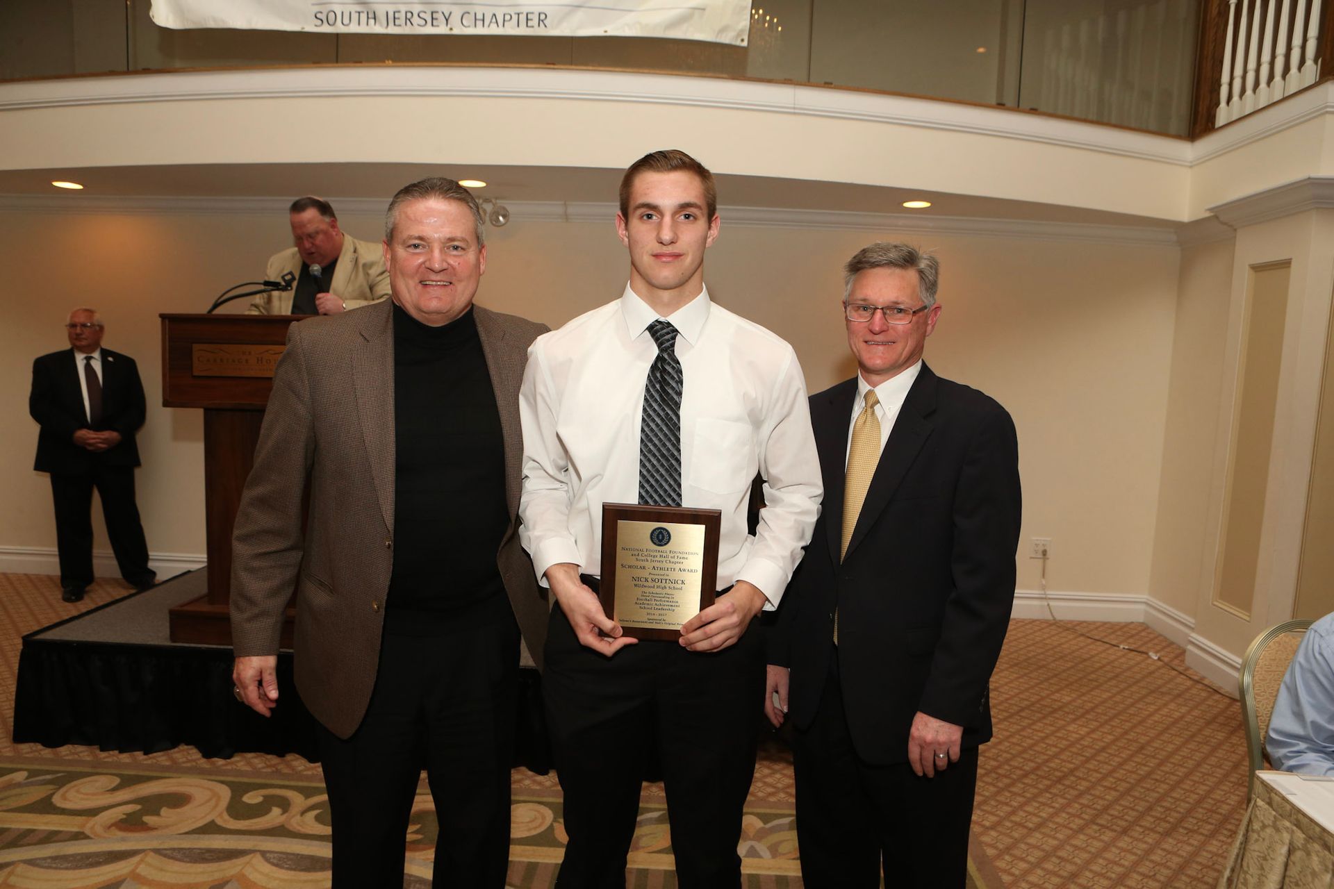 a man in a white shirt and tie is holding a plaque