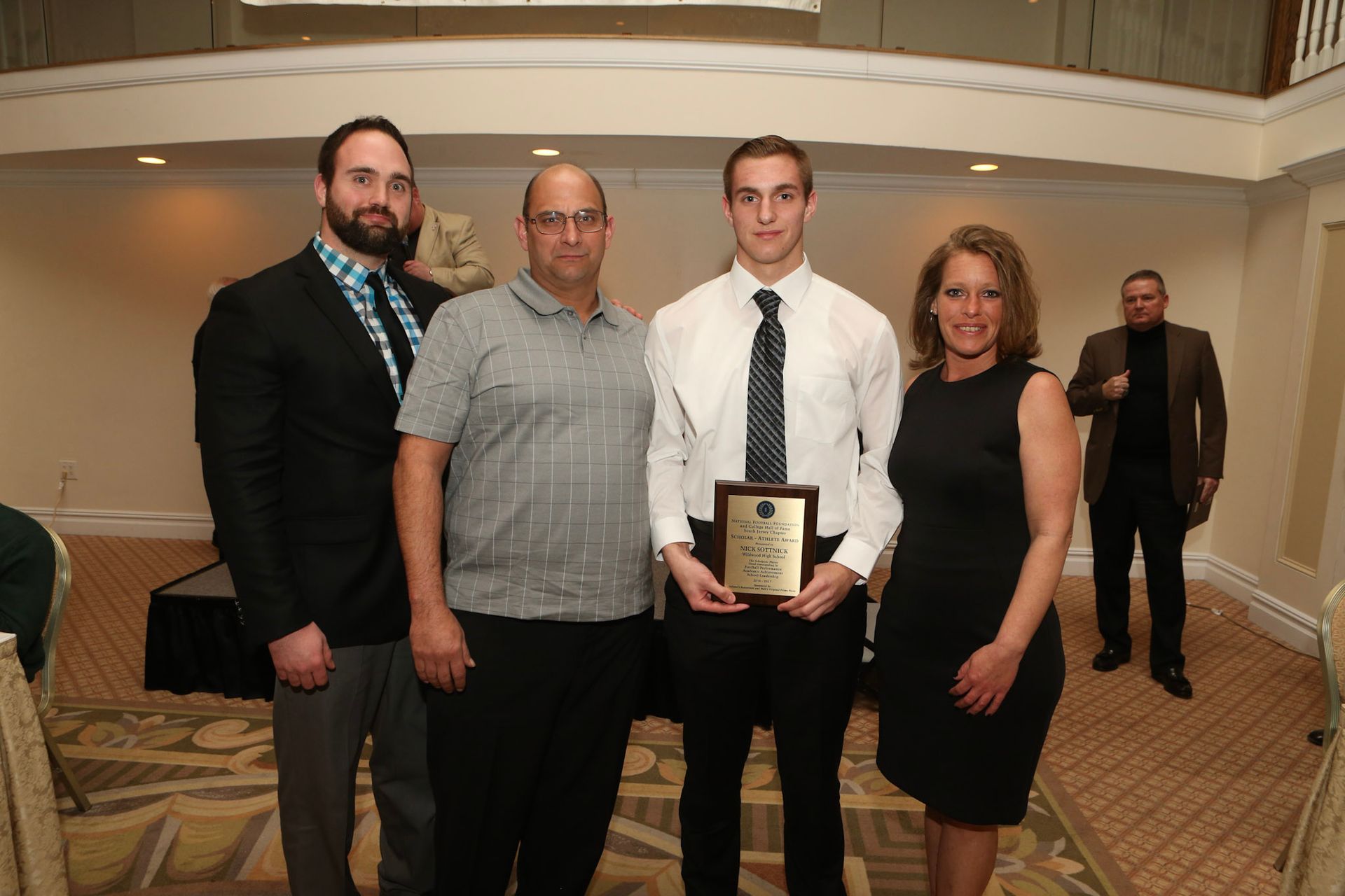 a group of people posing for a picture with a man holding a plaque