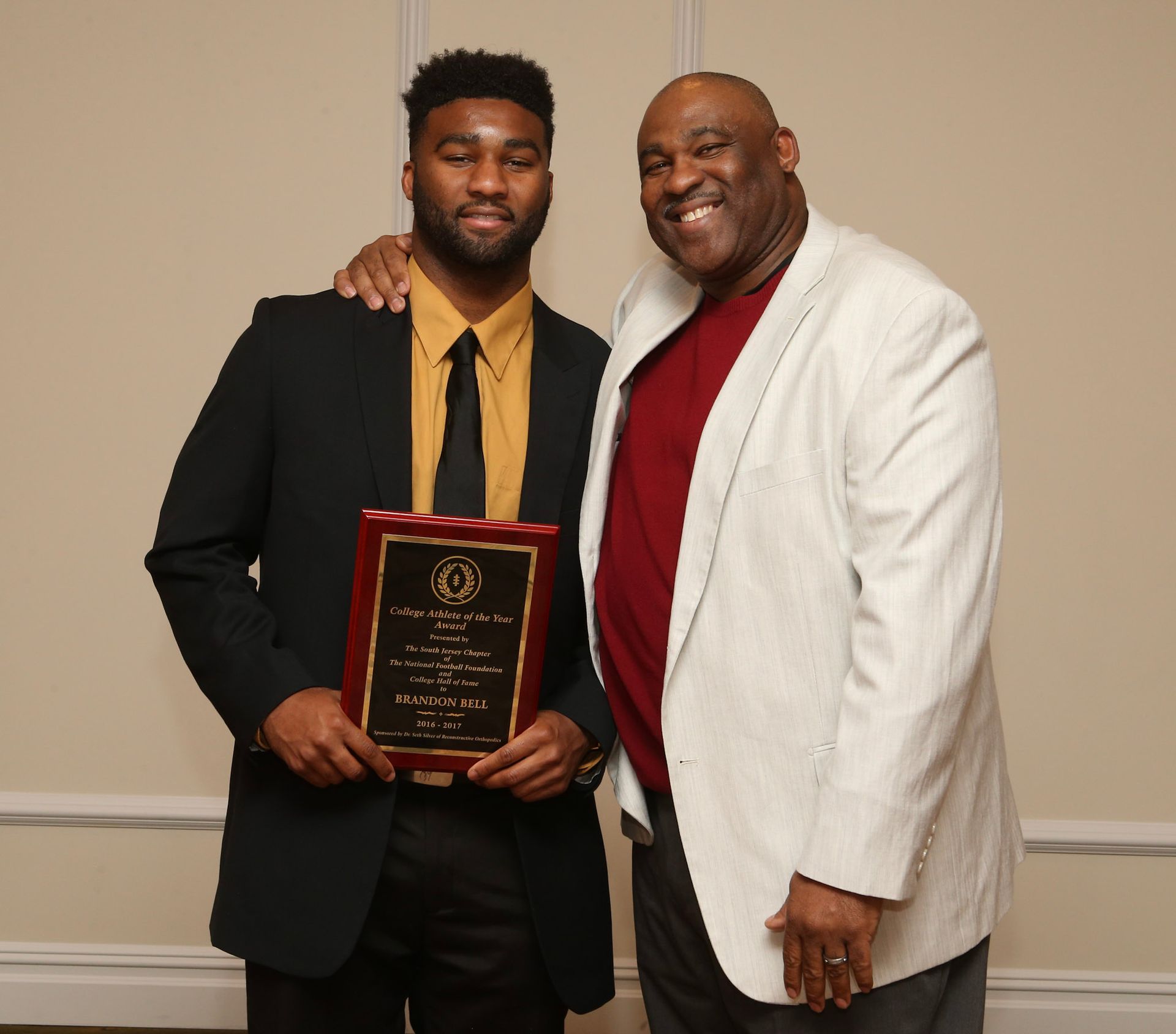 two men standing next to each other one of whom is holding a plaque