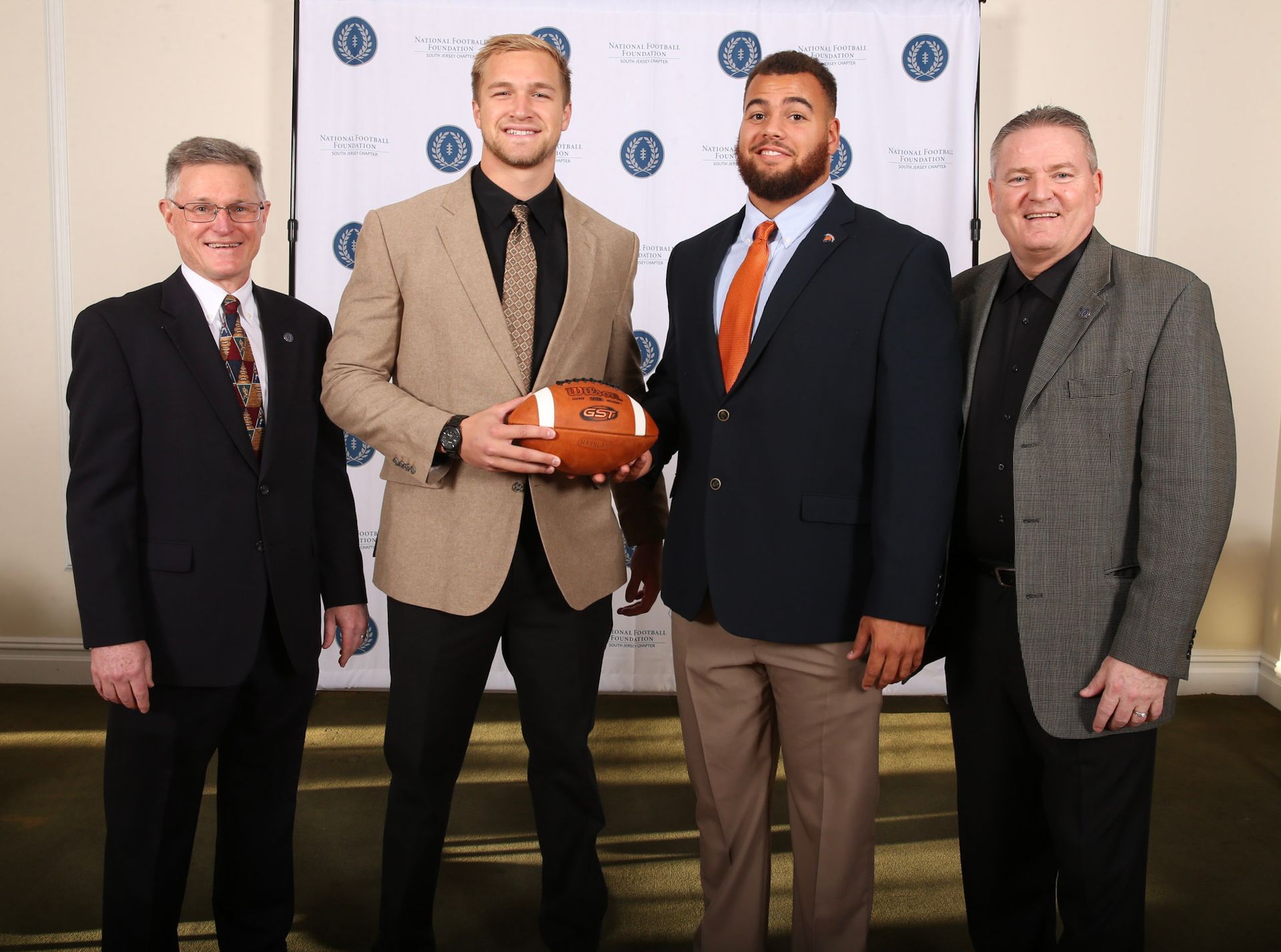 a man in a suit is holding a football with the number 55 on it