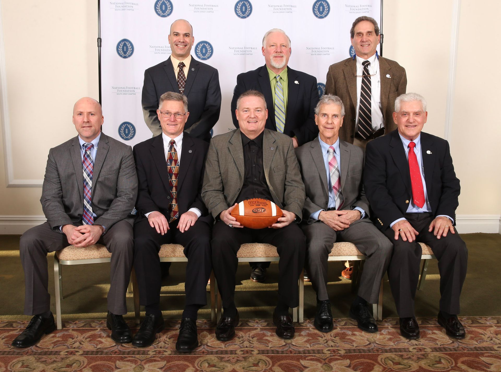 a group of men posing for a picture with one man holding a football