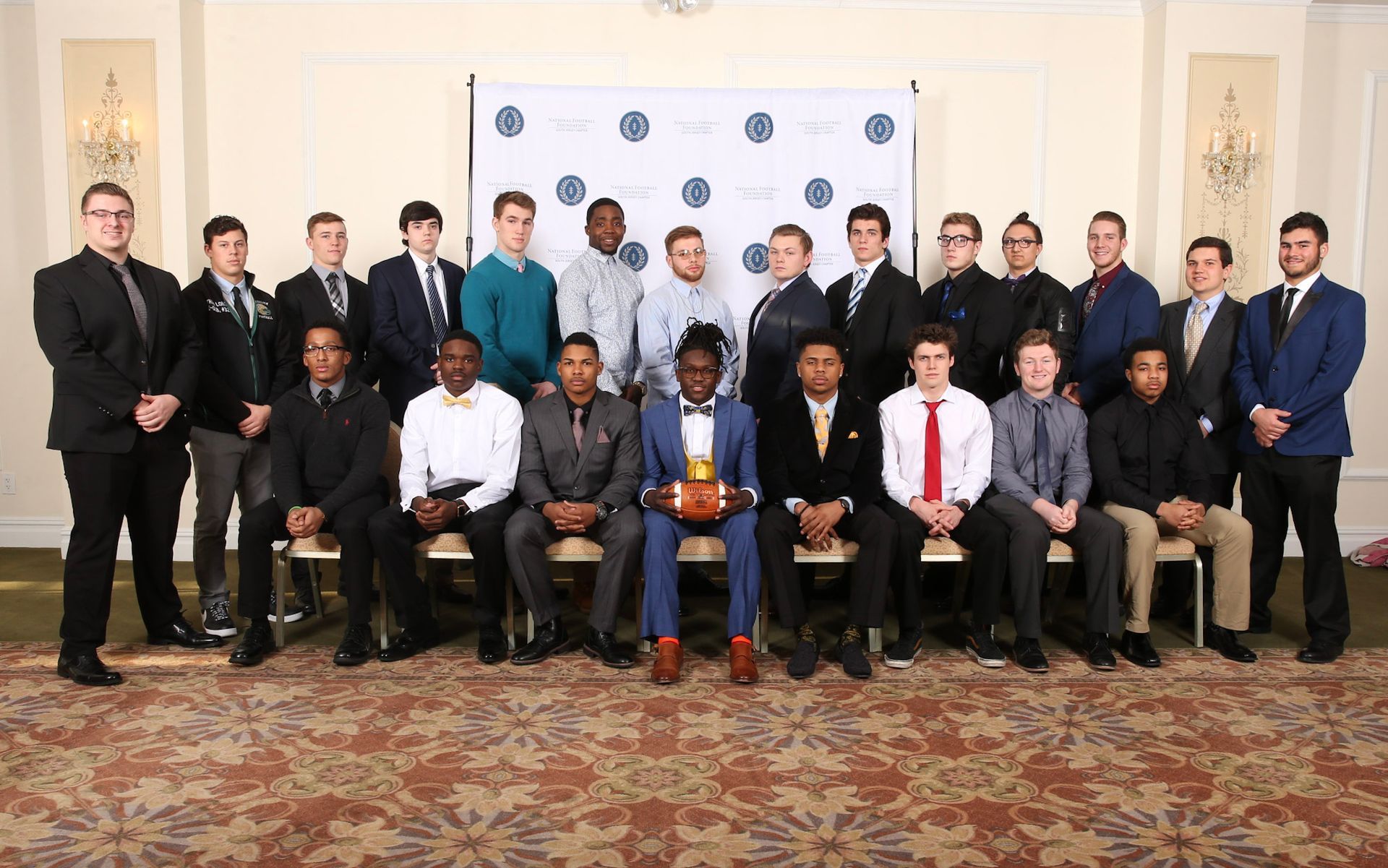 a group of men posing for a picture with one man holding a football