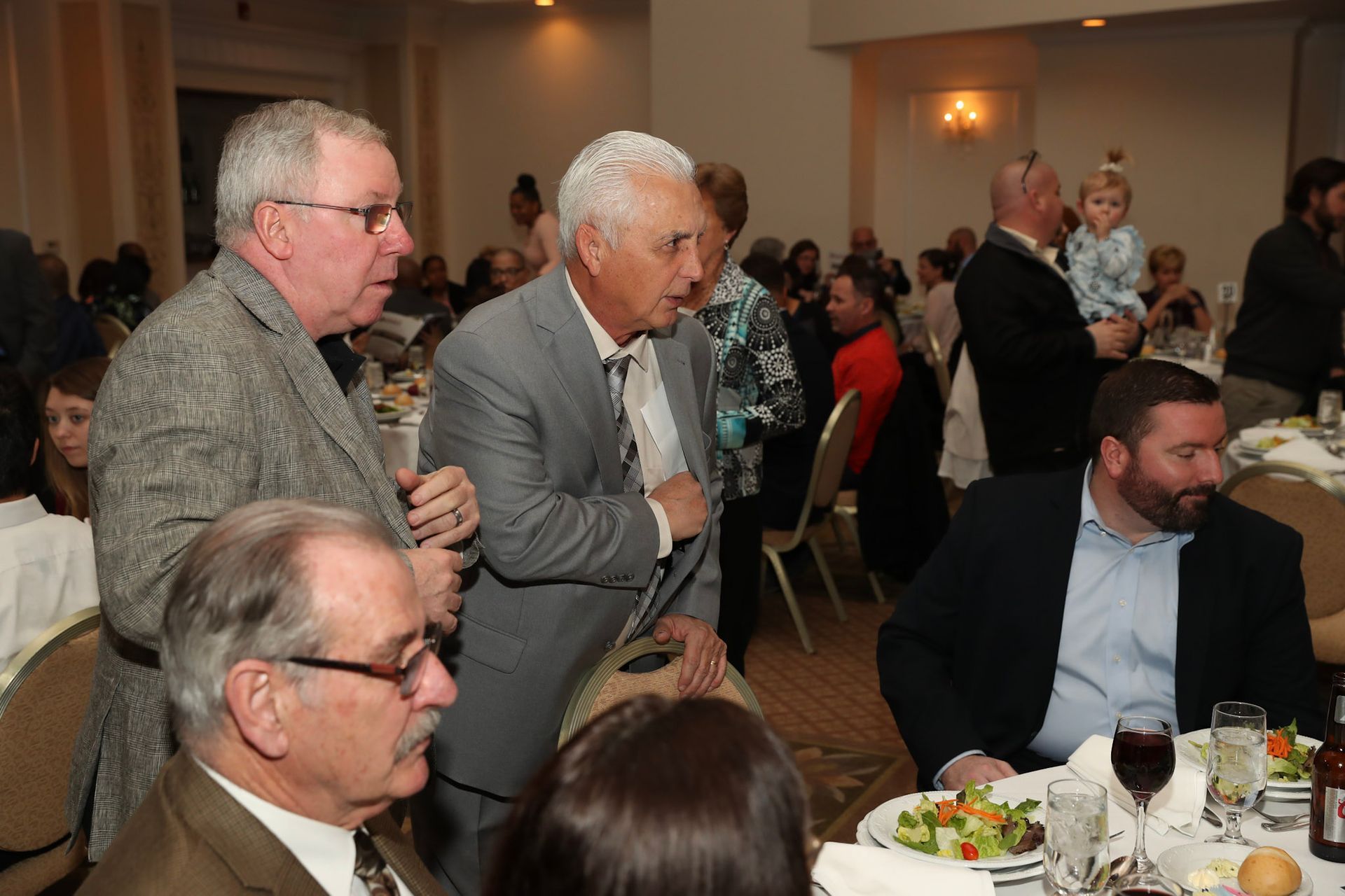 a group of men are sitting at a table with plates of food