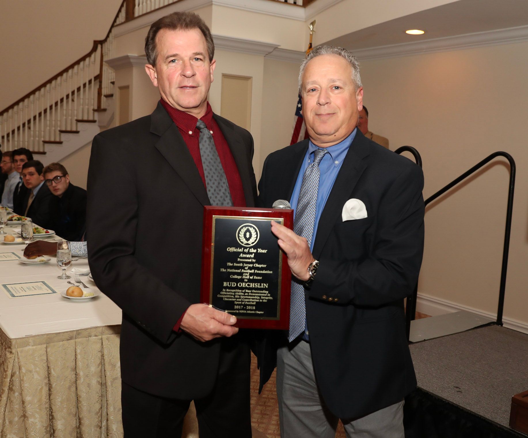 two men standing next to each other holding a plaque