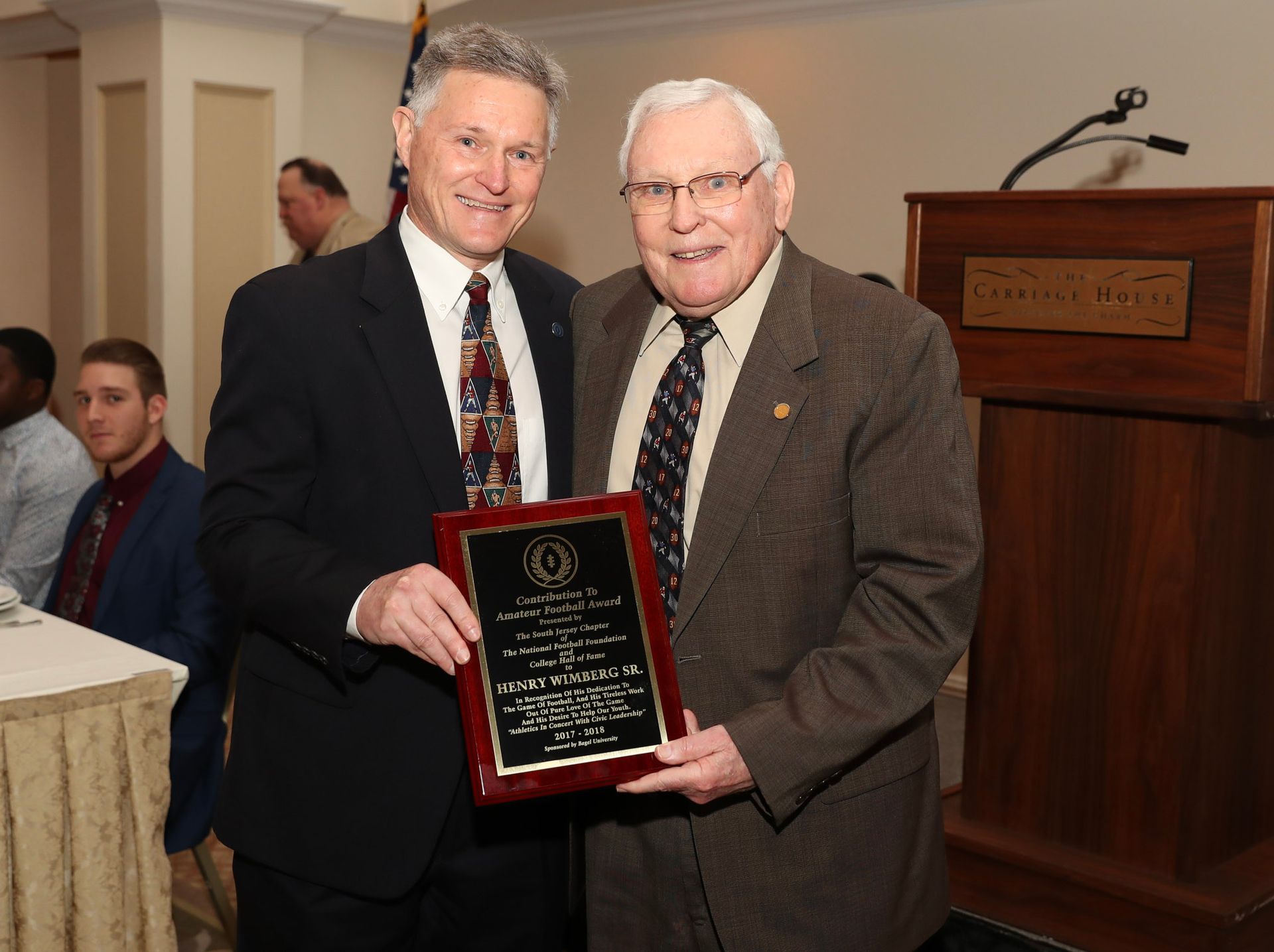 two men are posing for a picture and one is holding a plaque