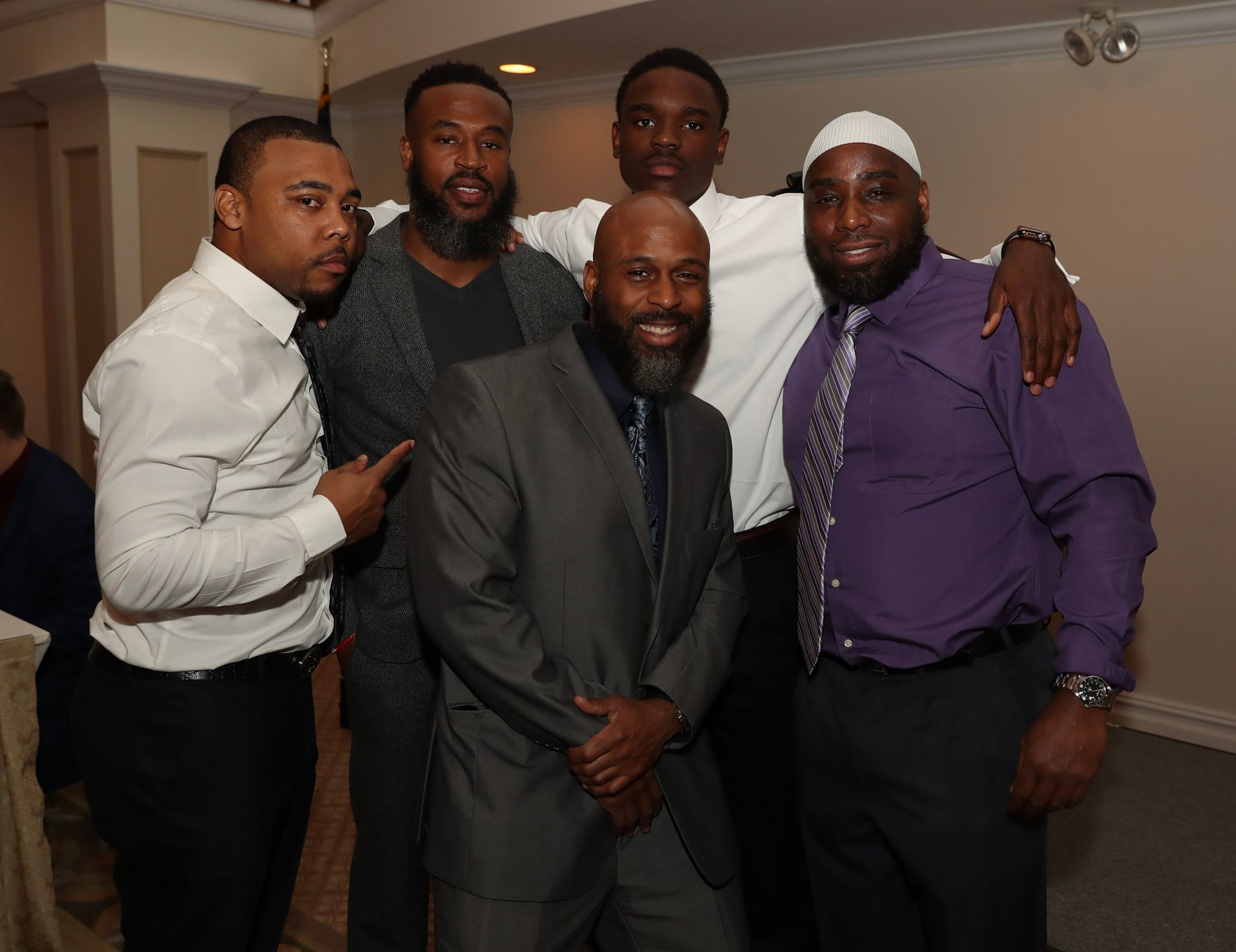a group of men posing for a picture with one wearing a purple shirt