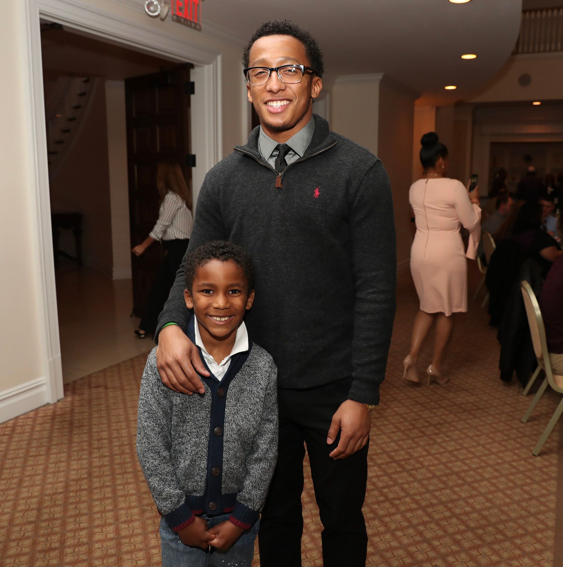 a man and a boy pose for a picture in front of an exit sign