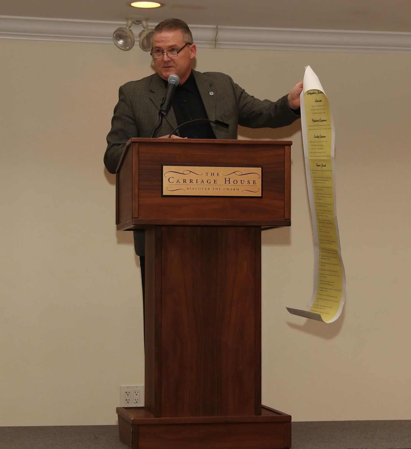 a man stands behind a podium holding a piece of paper with the number 1 on it