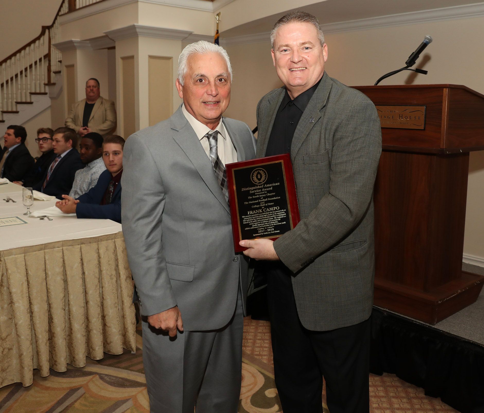 two men standing next to each other holding a plaque
