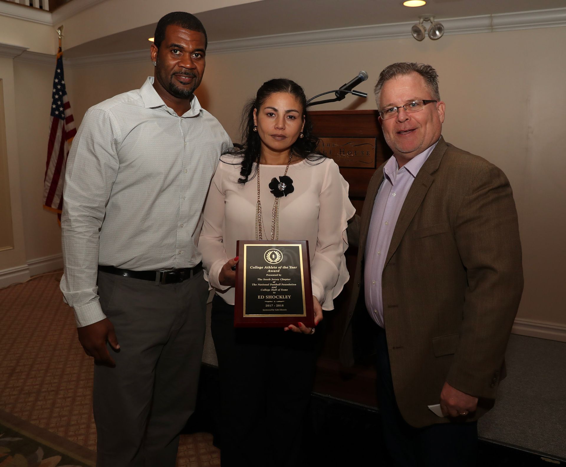 two men and a woman pose for a picture while the woman holds an award