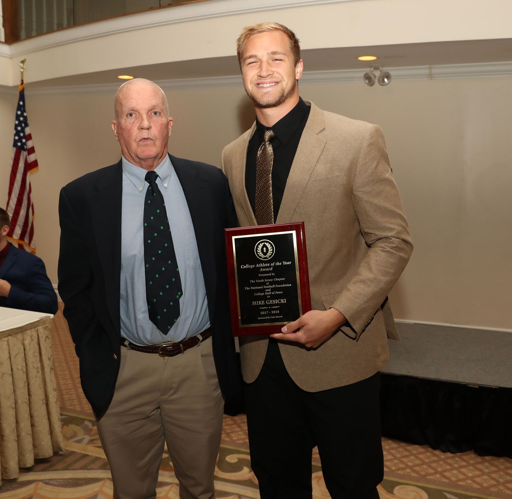 two men standing next to each other one of whom is holding a plaque