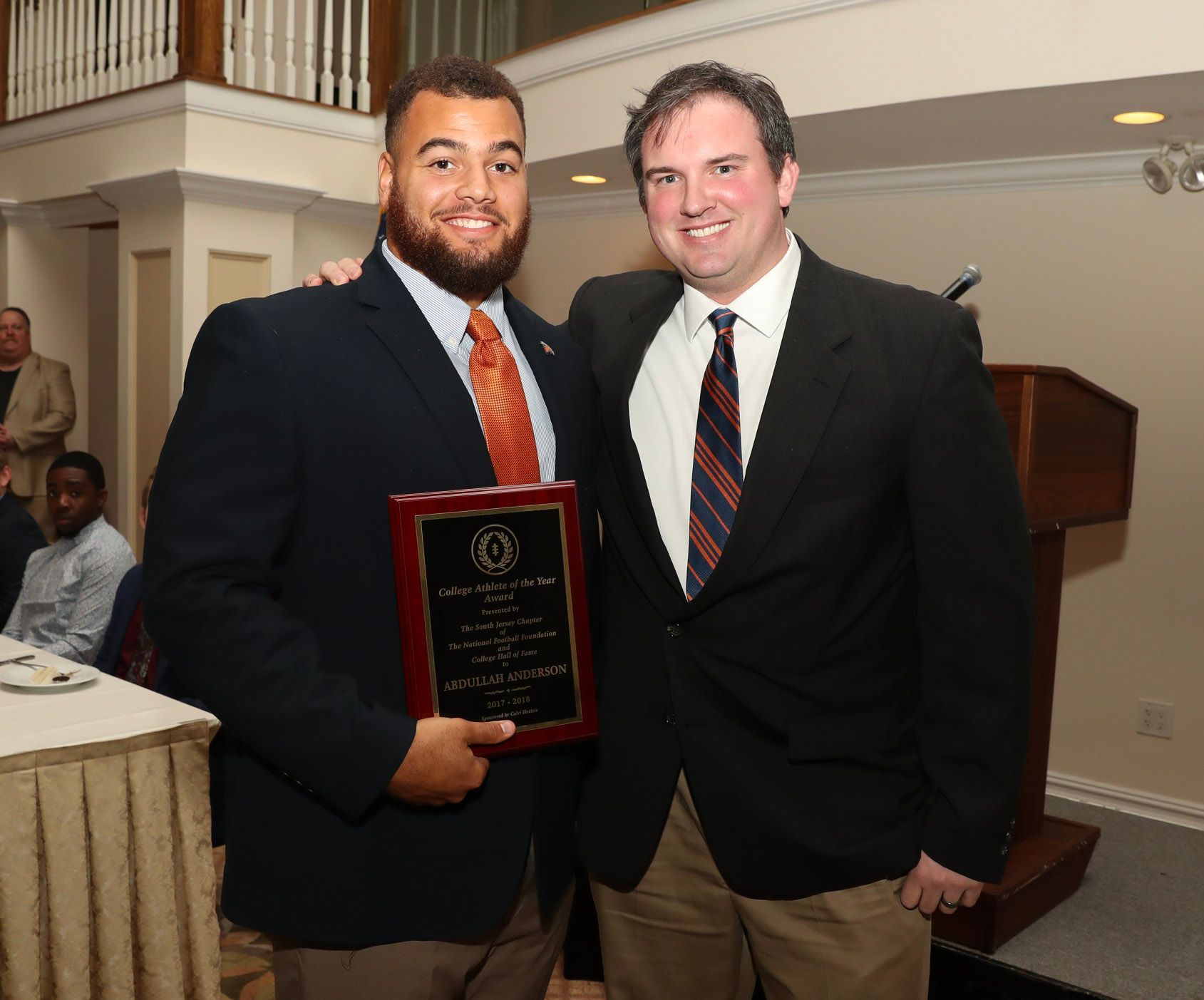 two men posing for a picture with one holding a plaque