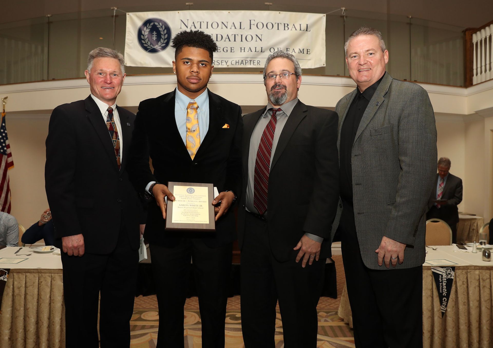 a man in a suit holds a plaque in front of a banner that says national football league