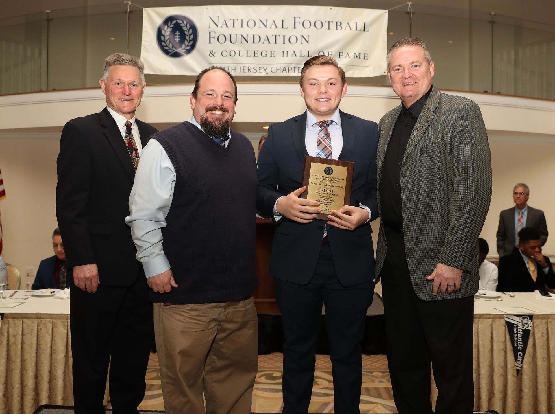 a group of men standing in front of a national football foundation banner