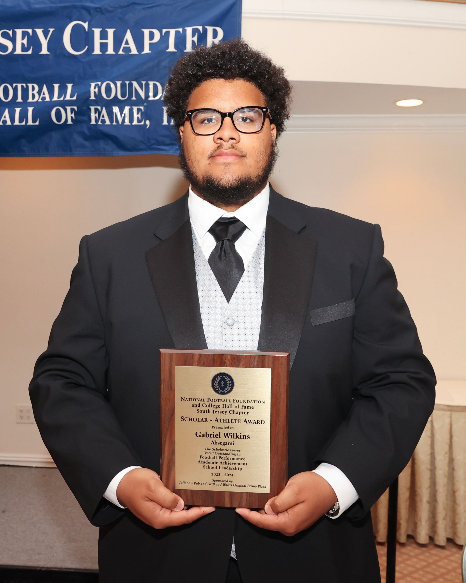 A scholar-athlete award winner holding an award plaque