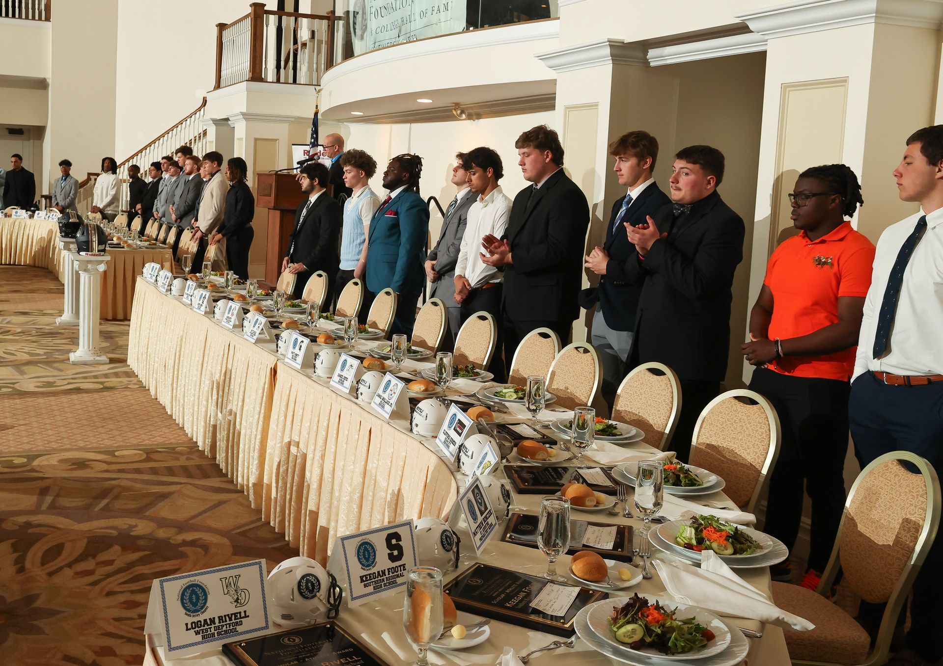 A group of men are standing in front of a long table with plates of food on it