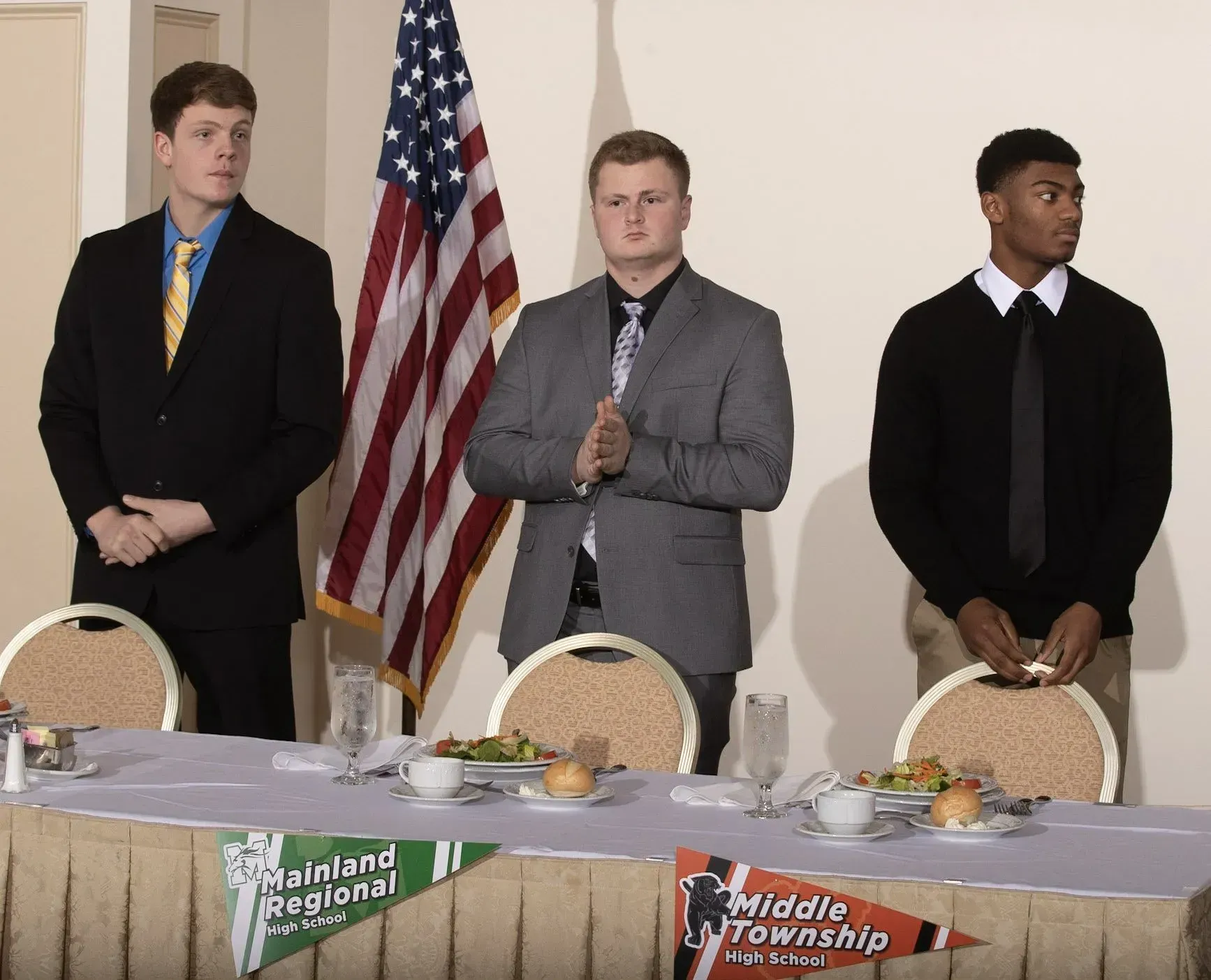 three men standing in front of a table with a banner that says middle township