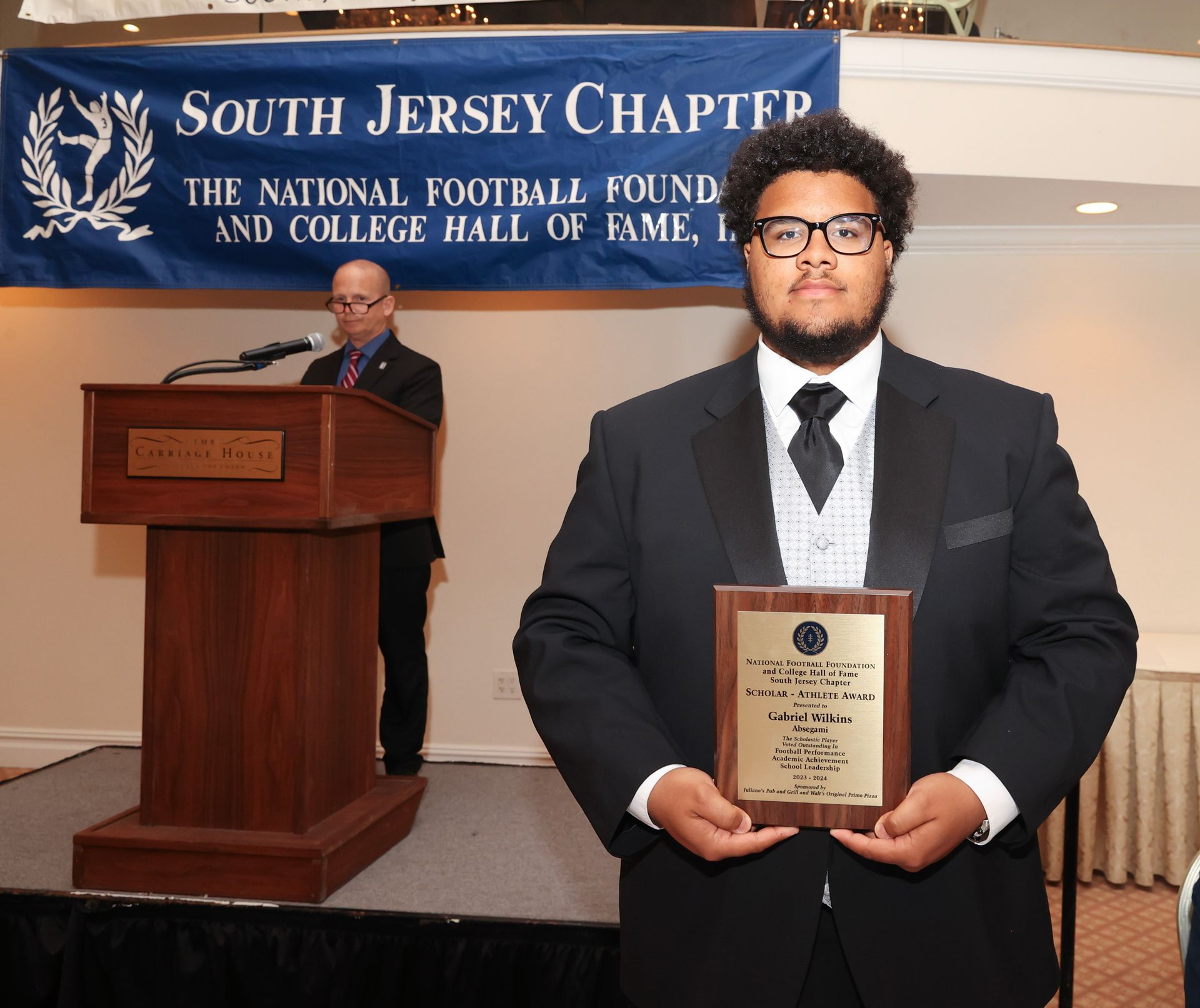 A man holding a plaque in front of a south jersey chapter banner