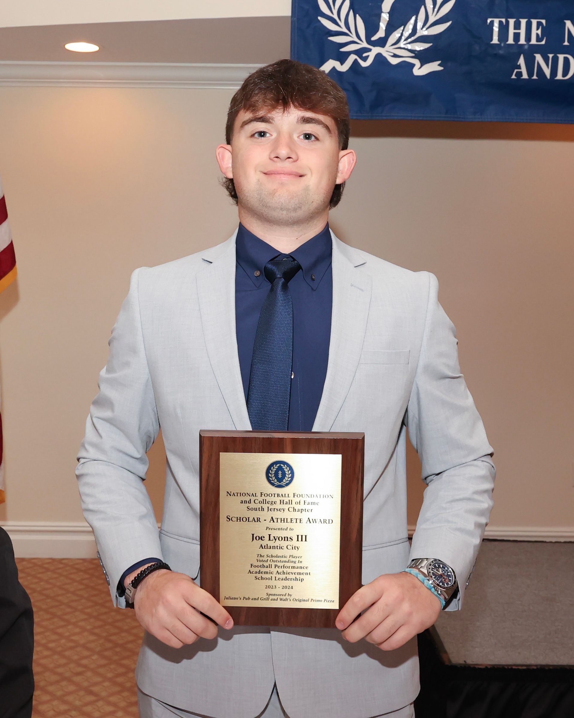 A man in a suit and tie is holding a plaque