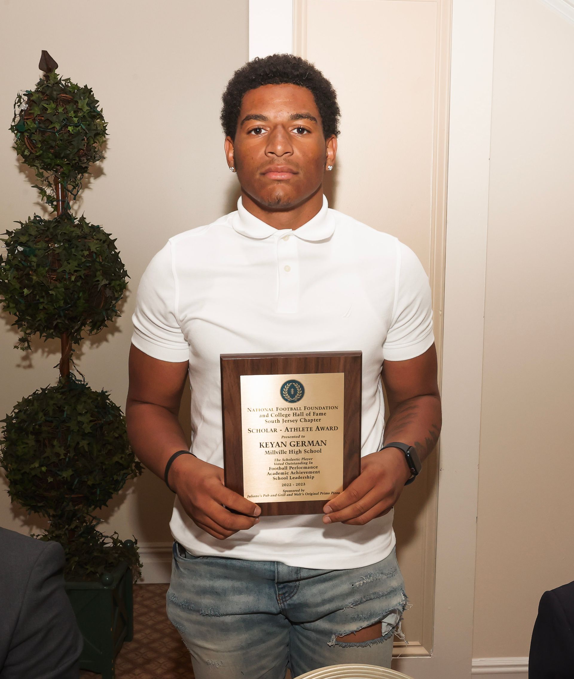 a young man in a white shirt is holding a plaque