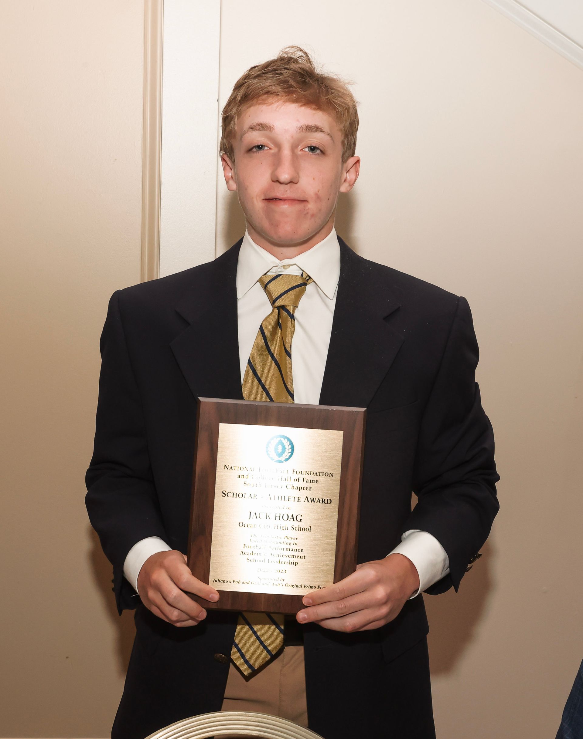 a young man in a suit and tie is holding a plaque
