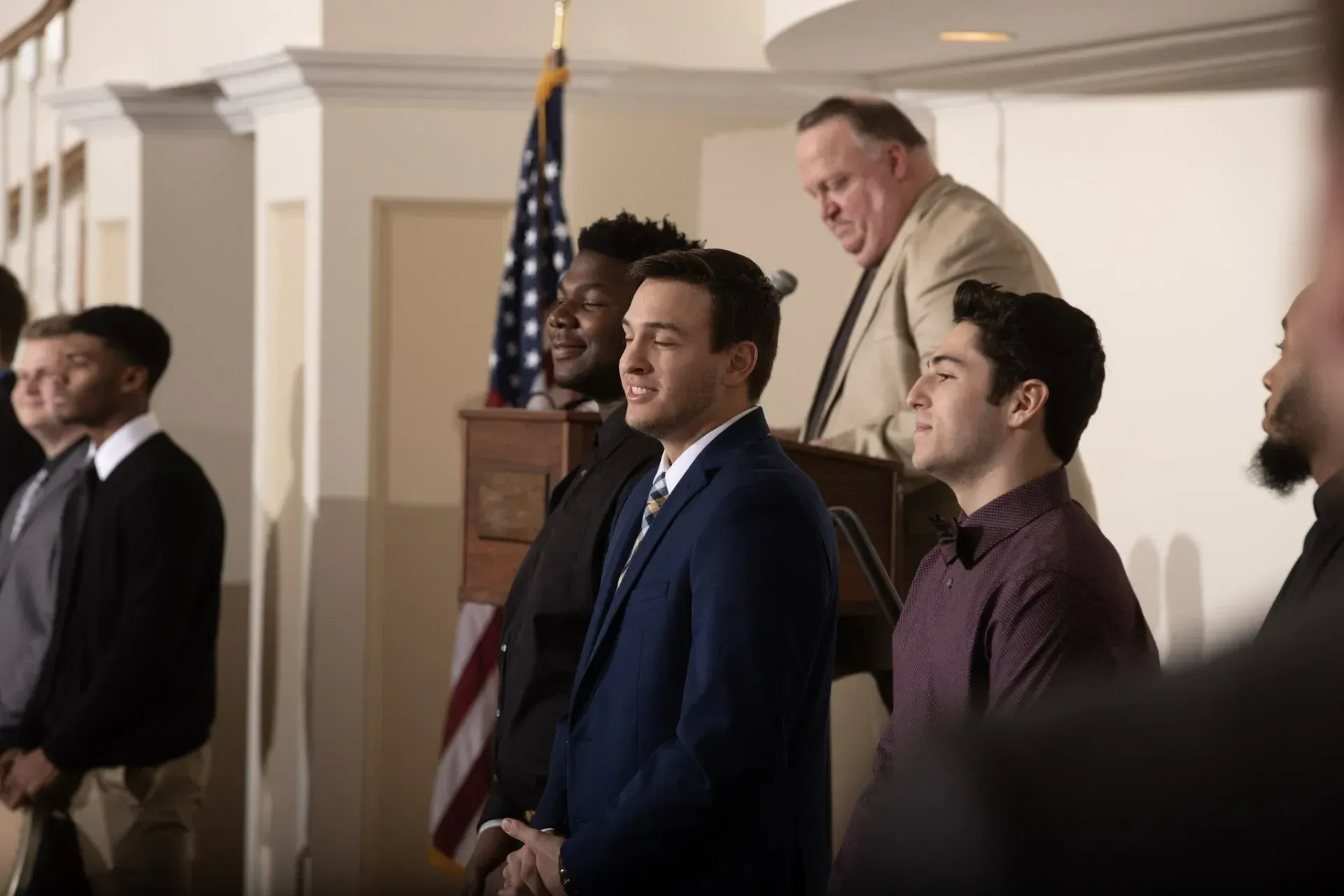 a group of men standing in front of a podium with an american flag in the background